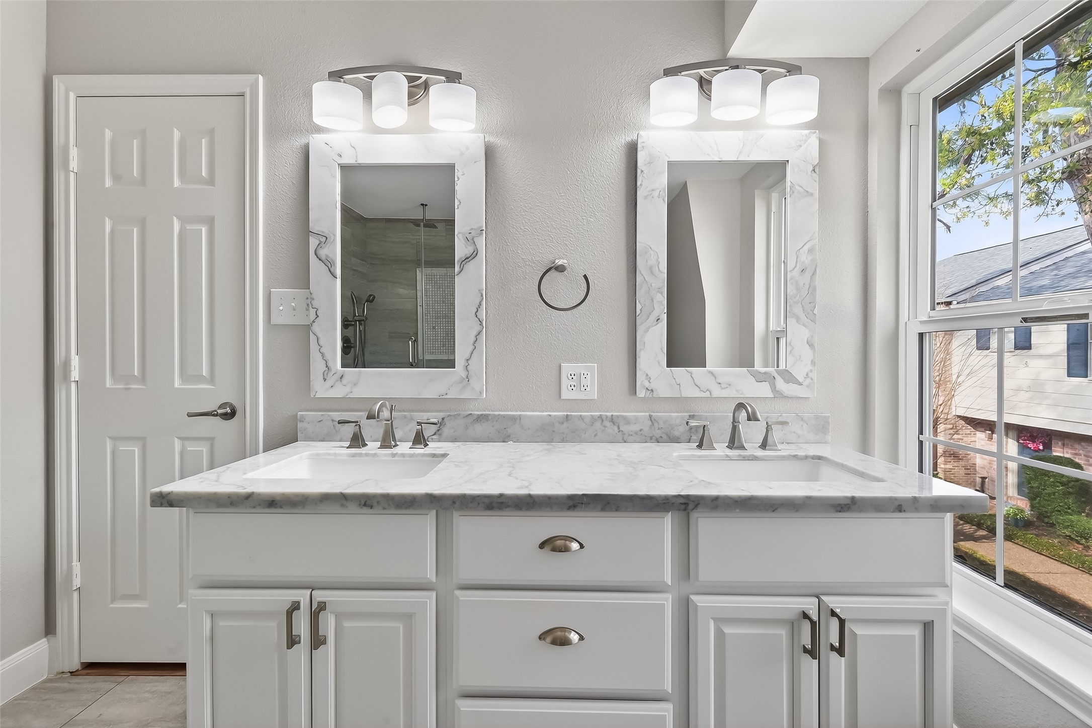 Updated primary bathroom with custom walk-in rain shower, marble finishes, and modern designer details.