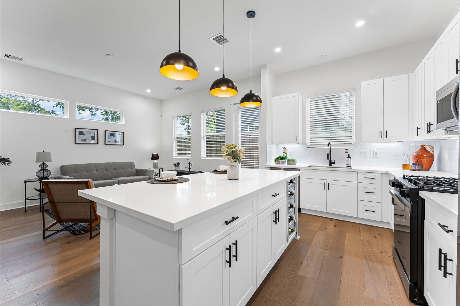This centrally positioned kitchen island serves as a stylish anchor within the open-concept layout, offering clear sightlines to the dining area, living space, and the backyard beyond. Its placement encourages seamless interaction, whether prepping meals or entertaining guests, while natural light pours in through the nearby windows. The islands sleek design and functional surface make it a hub of activity, framed by elegant finishes tying together comfort and sophistication.