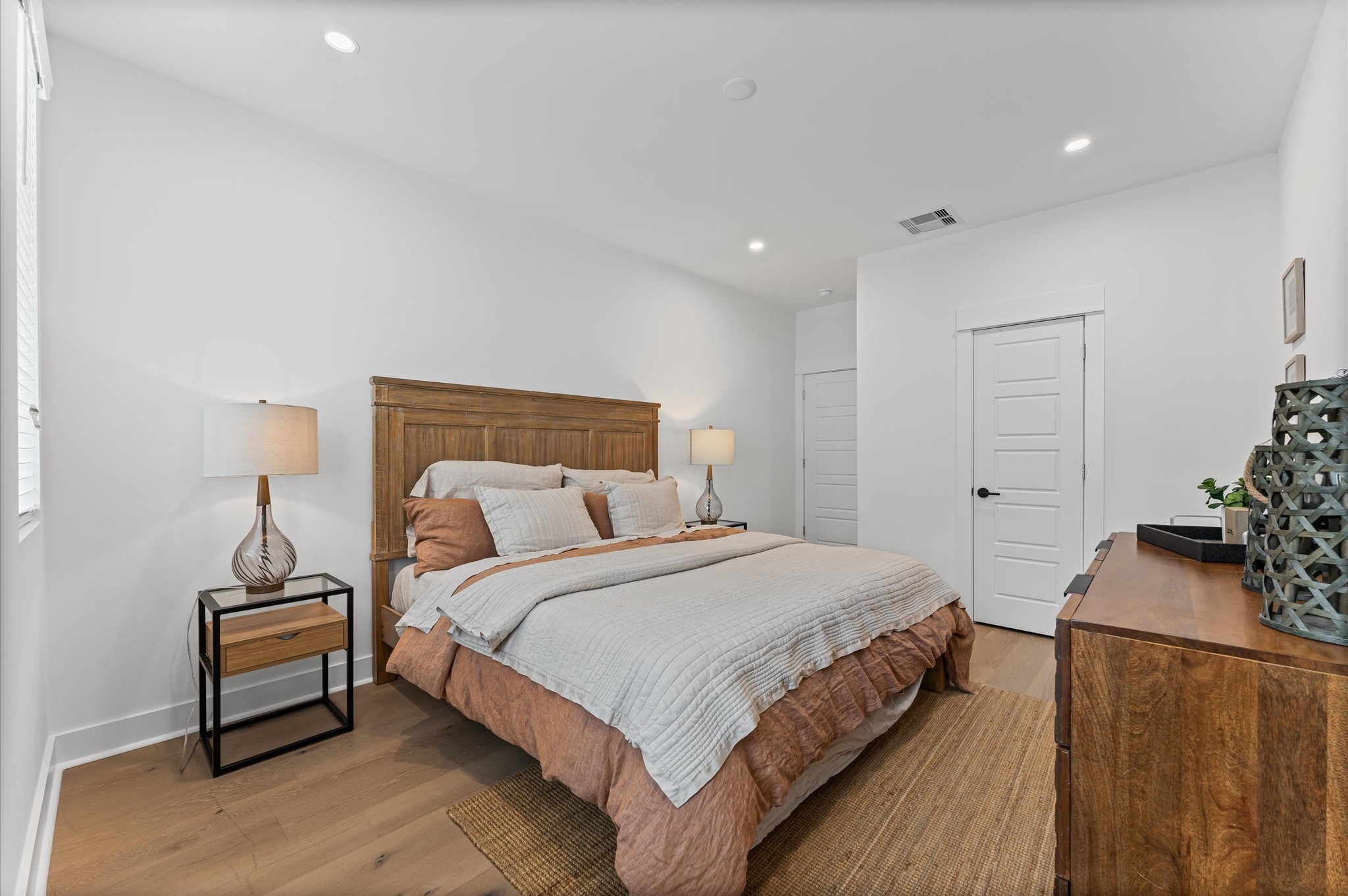 This spacious second-floor primary bedroom exudes modern elegance with its sleek engineered wood flooring that adds warmth and texture underfoot. Soaring high ceilings amplify the sense of openness, allowing natural light to cascade in and highlight the rooms architectural charm. Whether styled with minimalist furnishings or layered with cozy accents, the space offers a serene retreat elevated by its refined finishes and elevated vantage point.