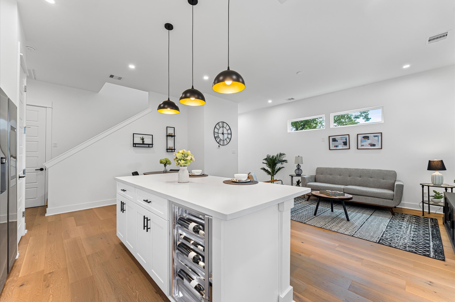 This centrally positioned kitchen island serves as a stylish anchor within the open-concept layout, offering clear sightlines to the dining area, living space, and the backyard beyond. Its placement encourages seamless interaction, whether prepping meals or entertaining guests, while natural light pours in through the nearby windows. The islands sleek design and functional surface make it a hub of activity, framed by elegant finishes tying together comfort and sophistication.