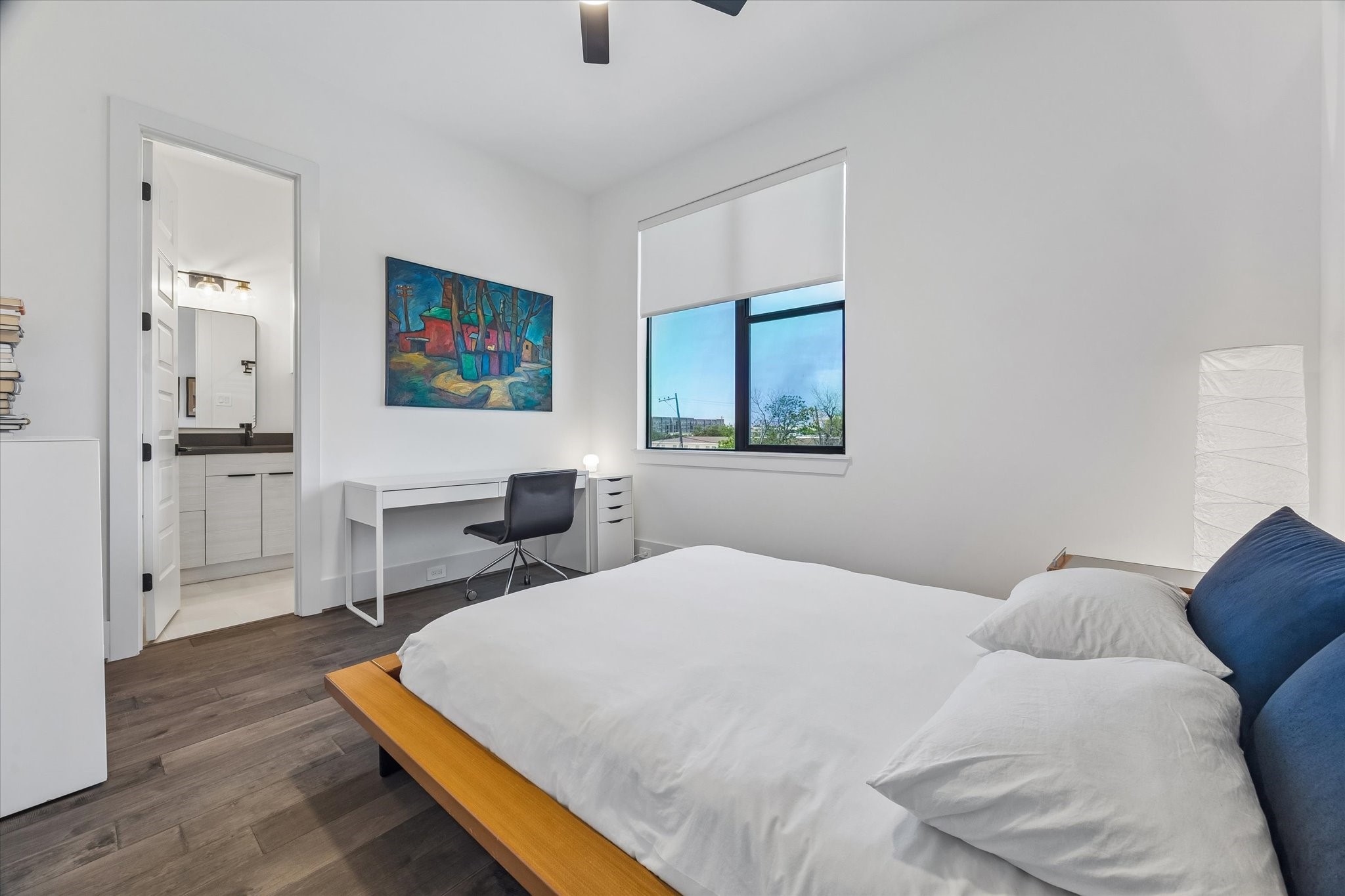 This bedroom offers another serene retreat with sleek hardwood floors, ample natural light, and a stunning sunset view.