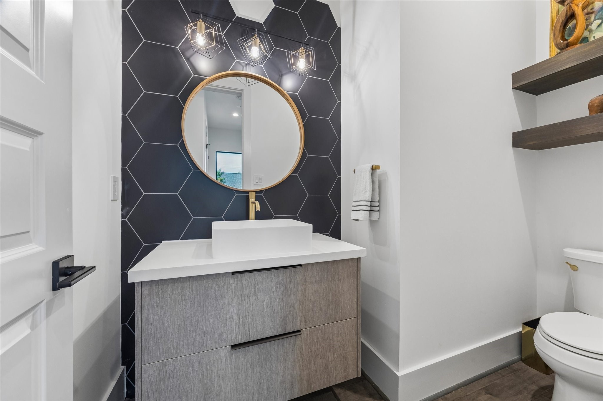 Stylish half bath with modern fixtures and a sleek hexagonal tile accent wall.