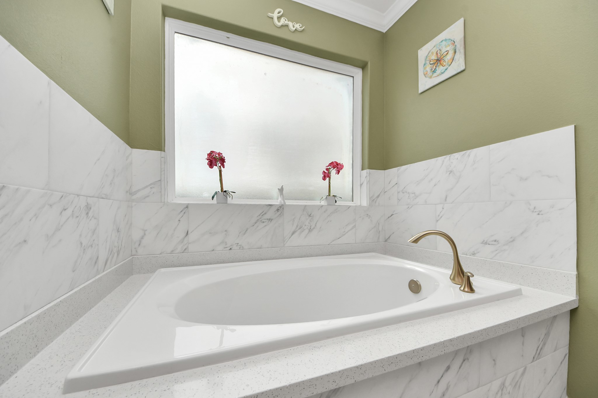 Corner soaking tub beneath a window in the primary bathroom.