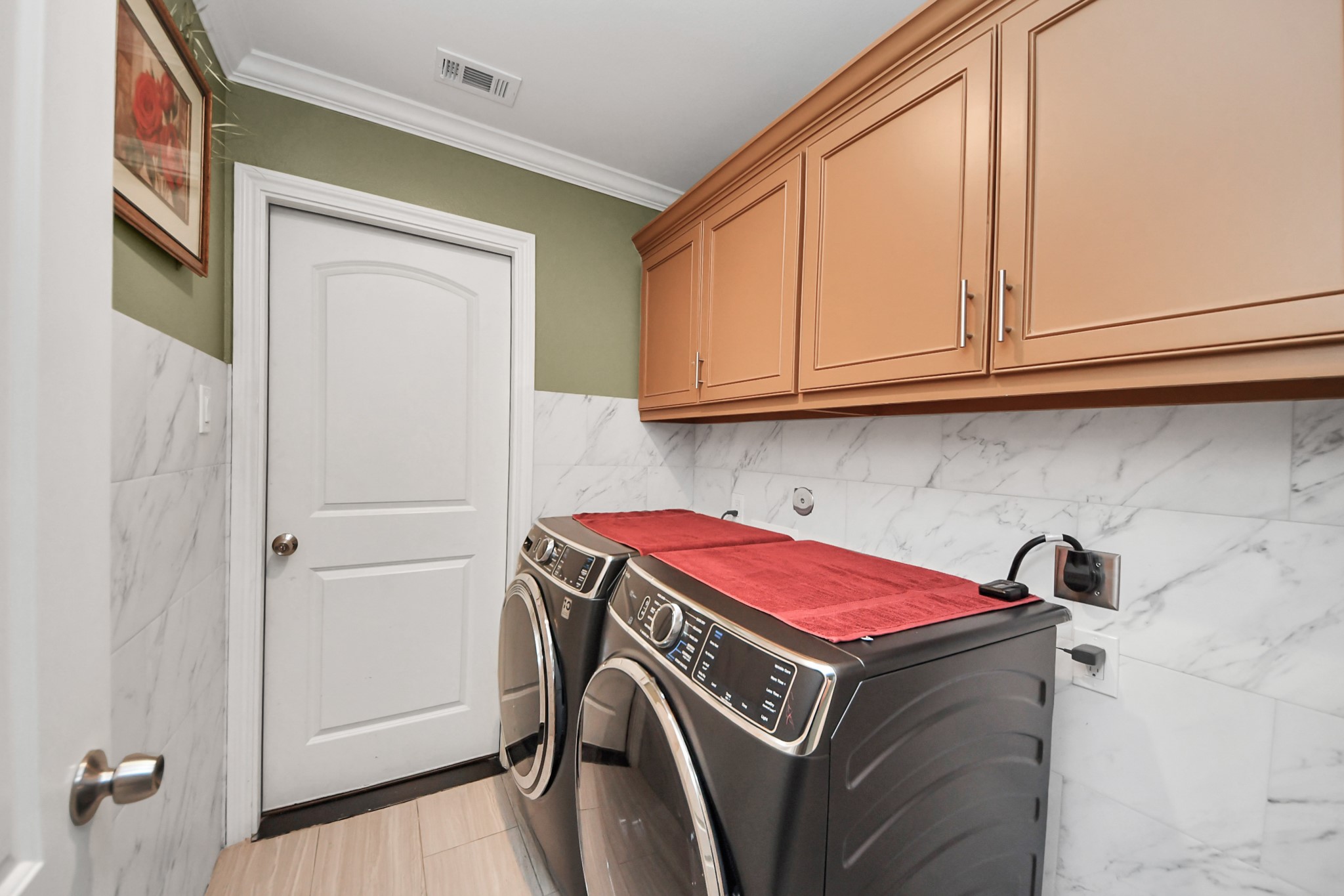 Laundry room with overhead cabinets and a utility door.