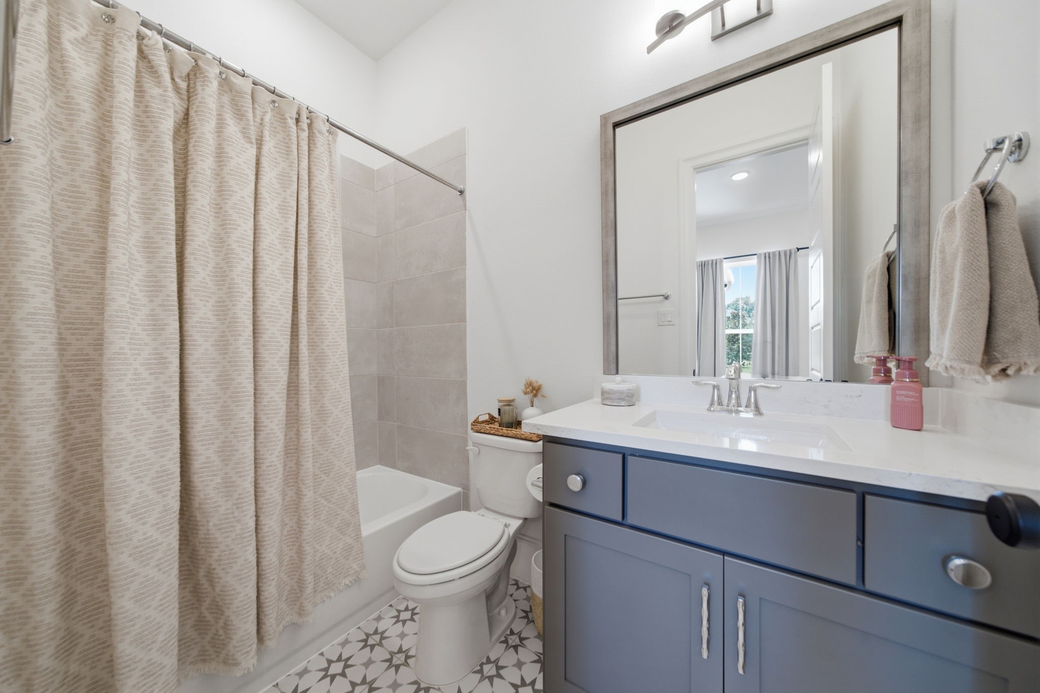 Charming bathroom with a modern vanity, elegant tile flooring, and a cozy tub-shower combo, creating a stylish and functional space.