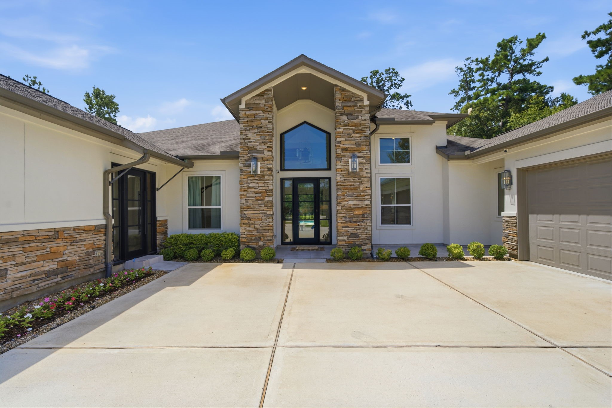 Stunning modern home with a grand entrance, featuring a striking stone faade and expansive driveway, set against a backdrop of lush greenery. Stunning modern home with a grand entrance, featuring a striking stone faade and expansive driveway, set against a backdrop of lush greenery.