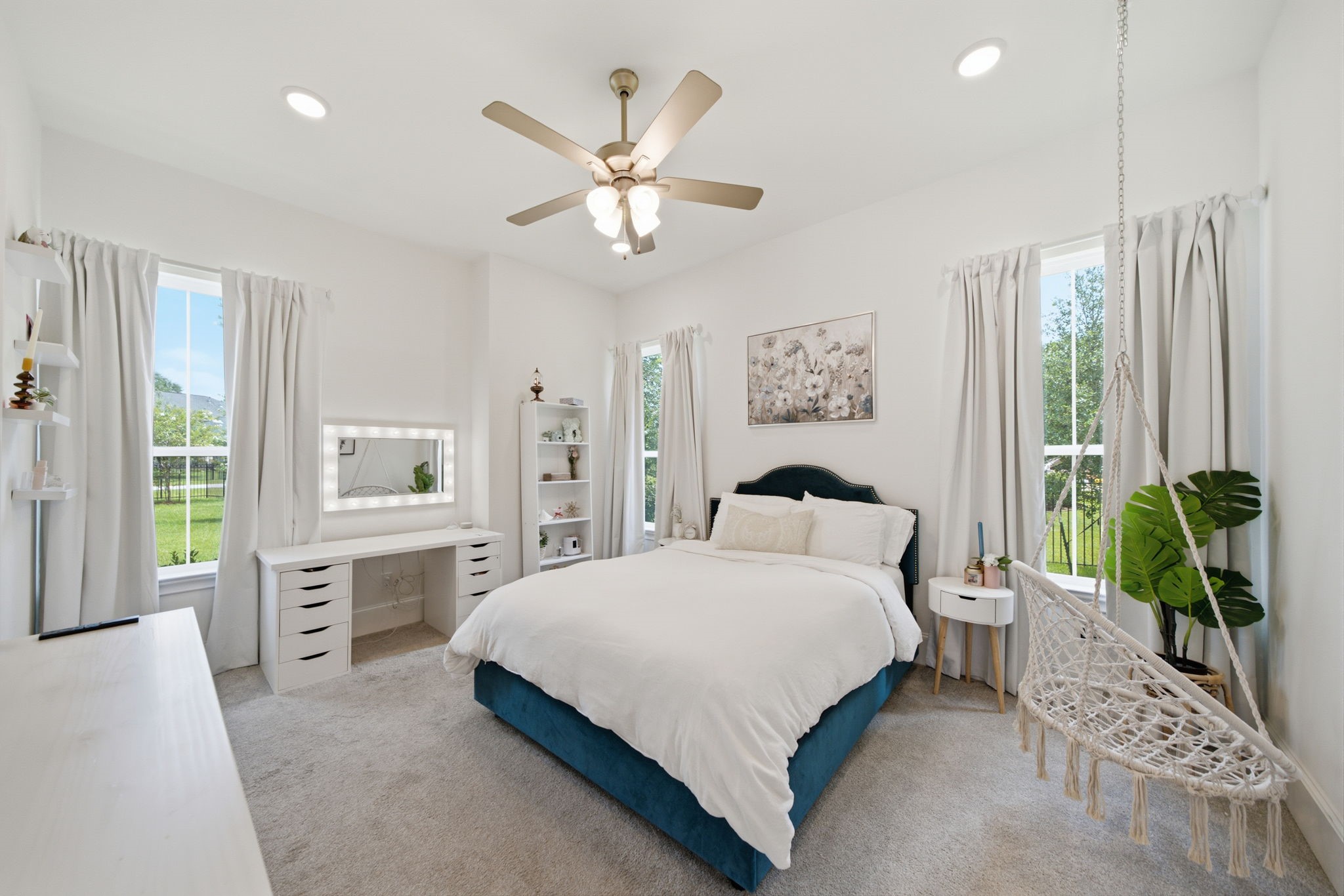 Bright and inviting bedroom with large windows, a cozy bed, and a charming hanging chair, offering a perfect blend of comfort and style.