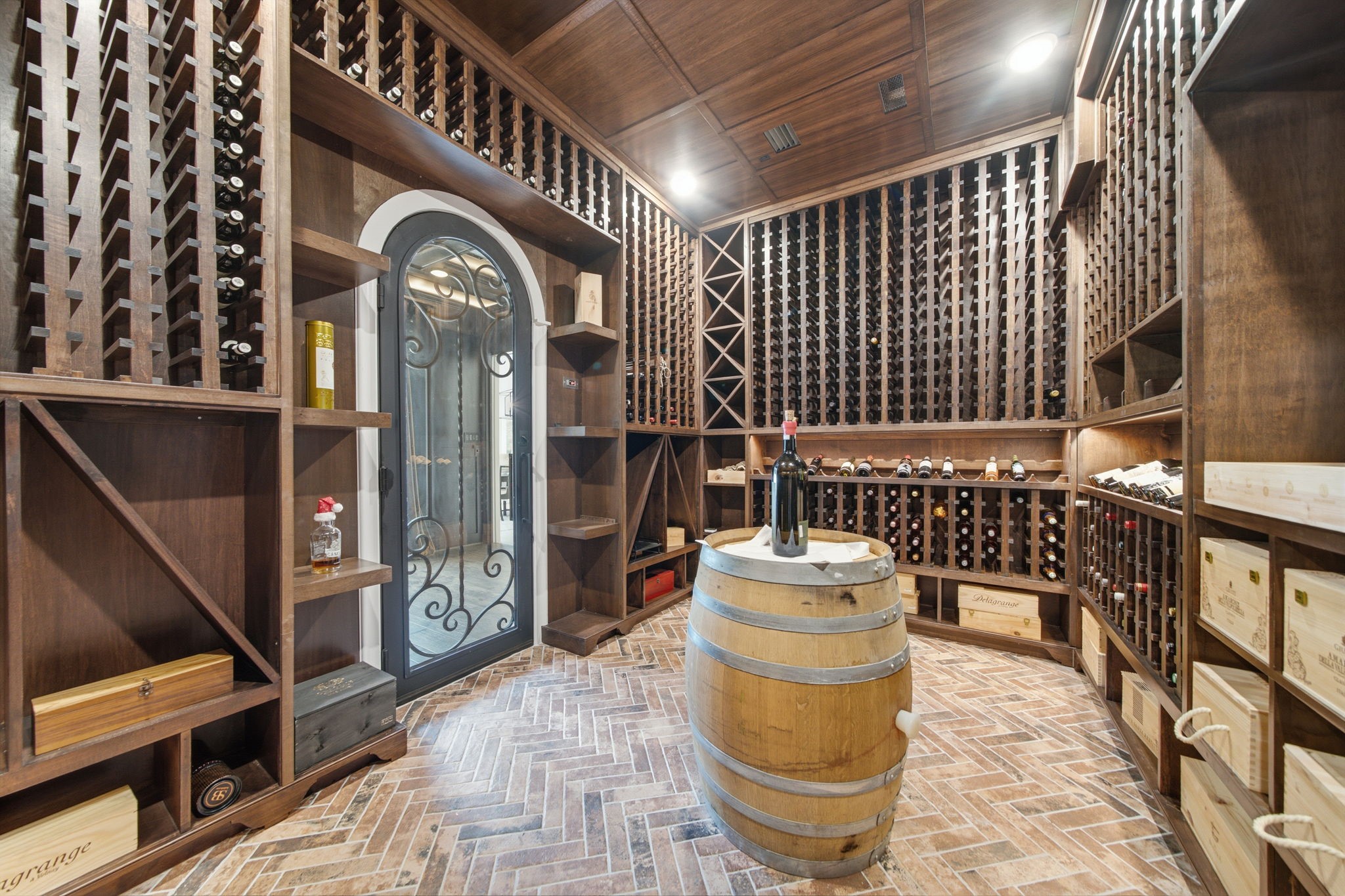 Luxurious wine cellar with custom wooden racks, elegant brick flooring, and a stylish barrel table centerpiece, perfect for wine enthusiasts.