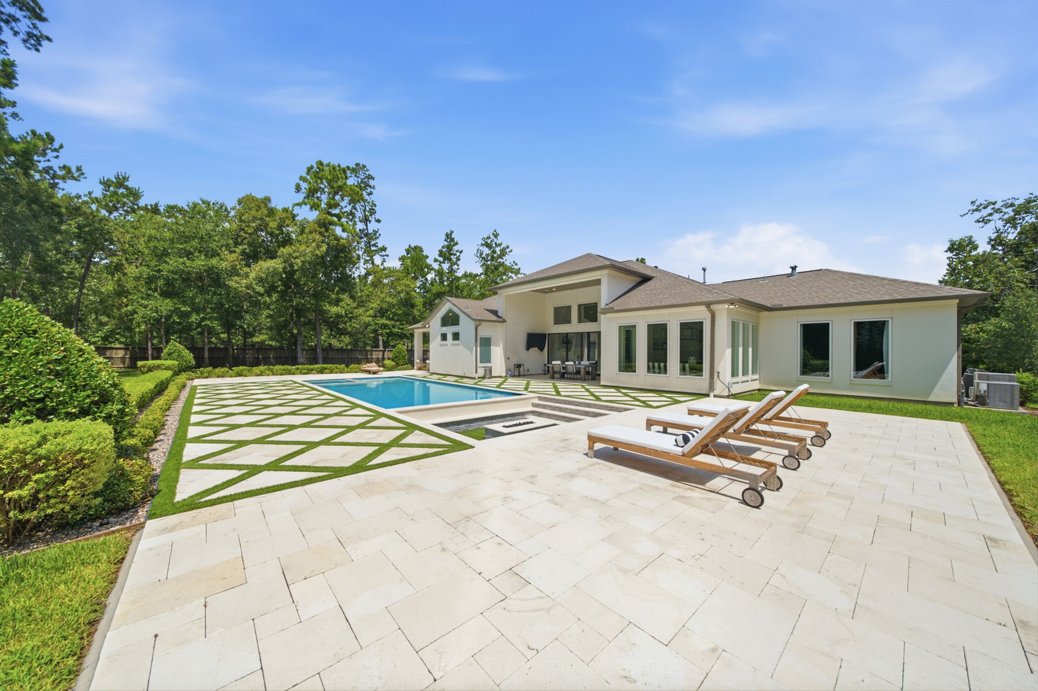 Luxurious modern home with a spacious backyard featuring a pristine pool, elegant patio, and lush landscaping, perfect for outdoor relaxation and entertaining.