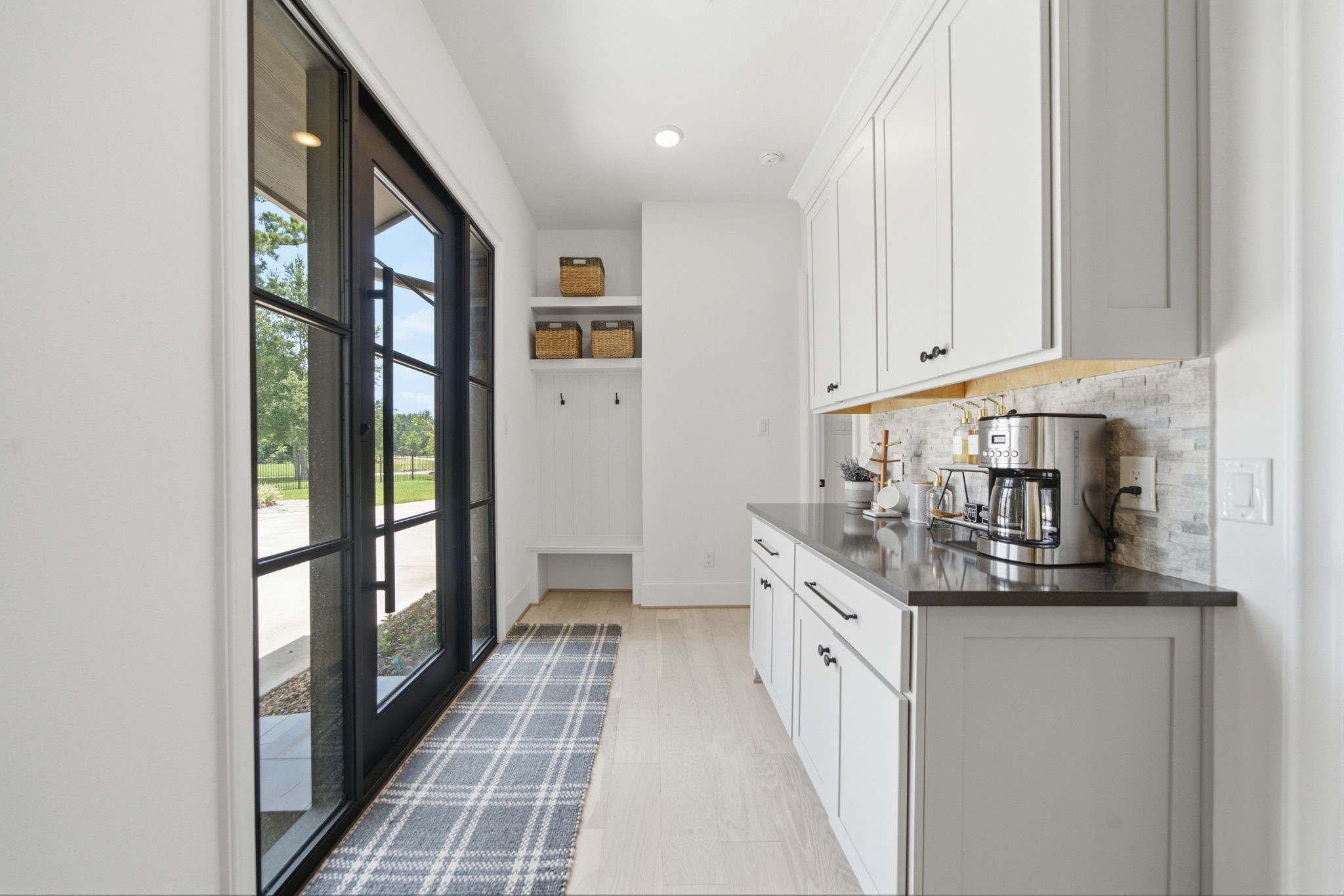 Bright and inviting mudroom with sleek cabinetry, ample storage, and large glass doors offering a view of the outdoors.