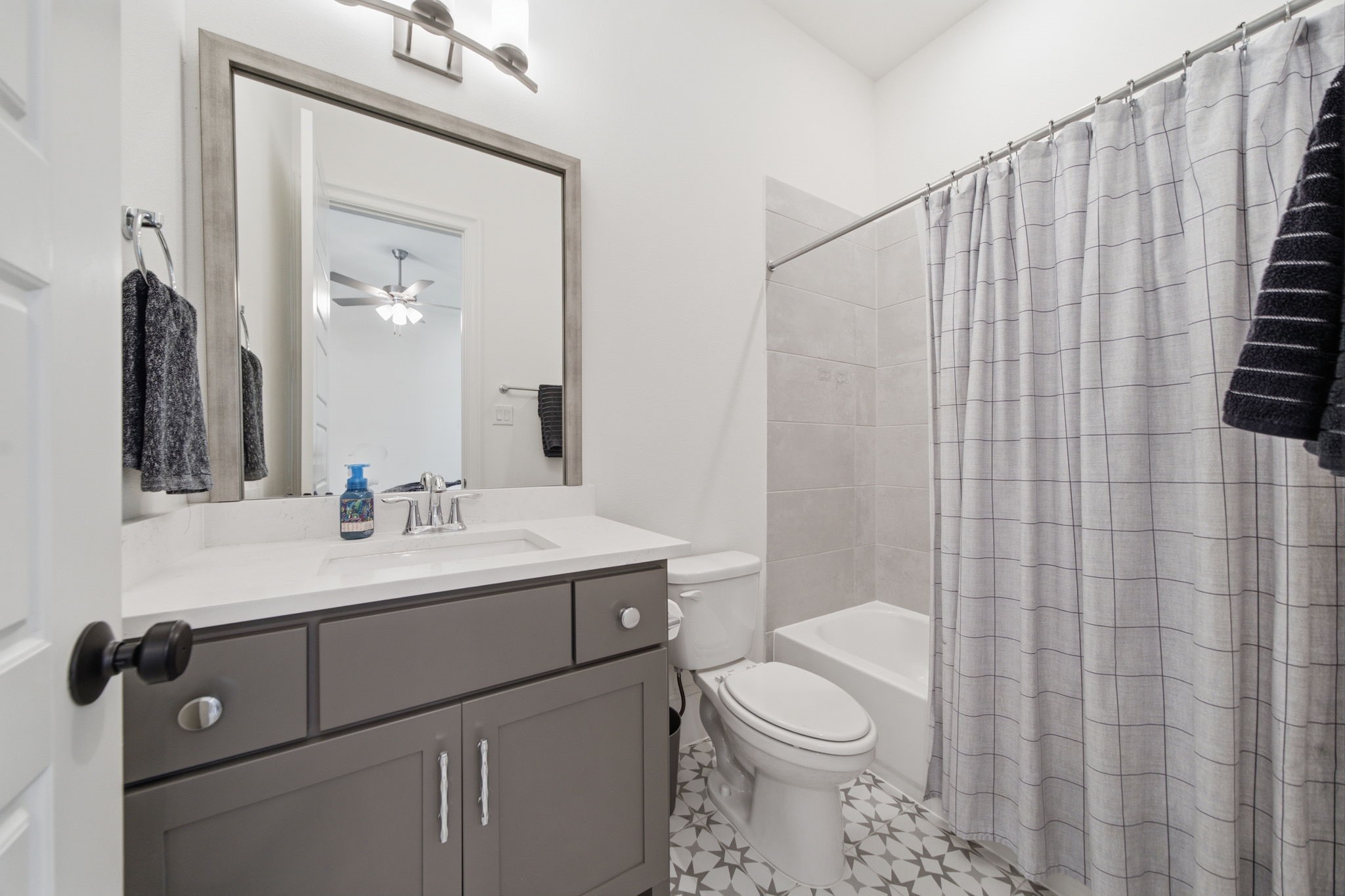 Modern bathroom with a sleek vanity, contemporary fixtures, and a stylish patterned tile floor.