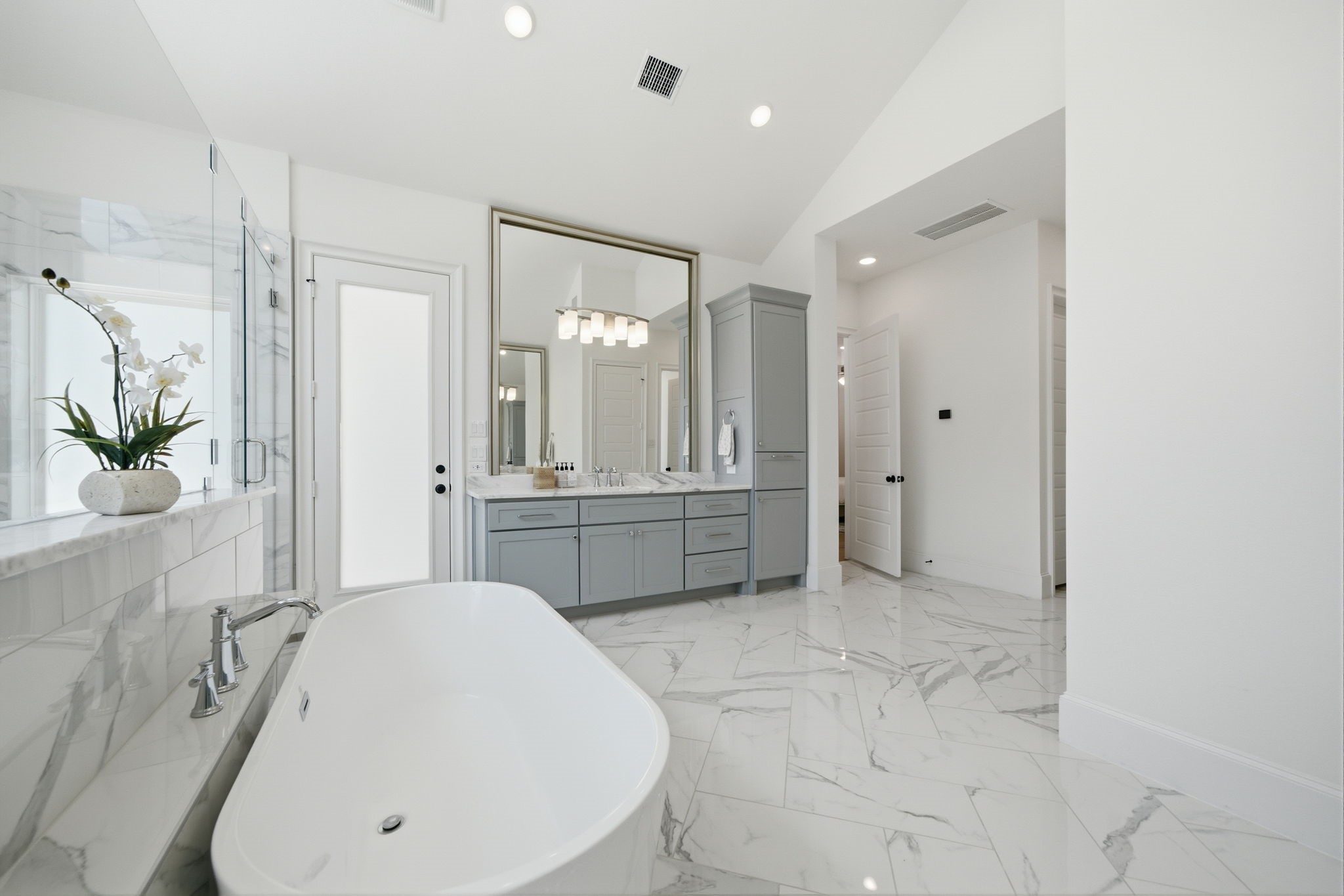 Luxurious bathroom featuring a freestanding tub, elegant marble flooring, and a sleek vanity with ample storage, all enhanced by soft natural lighting.