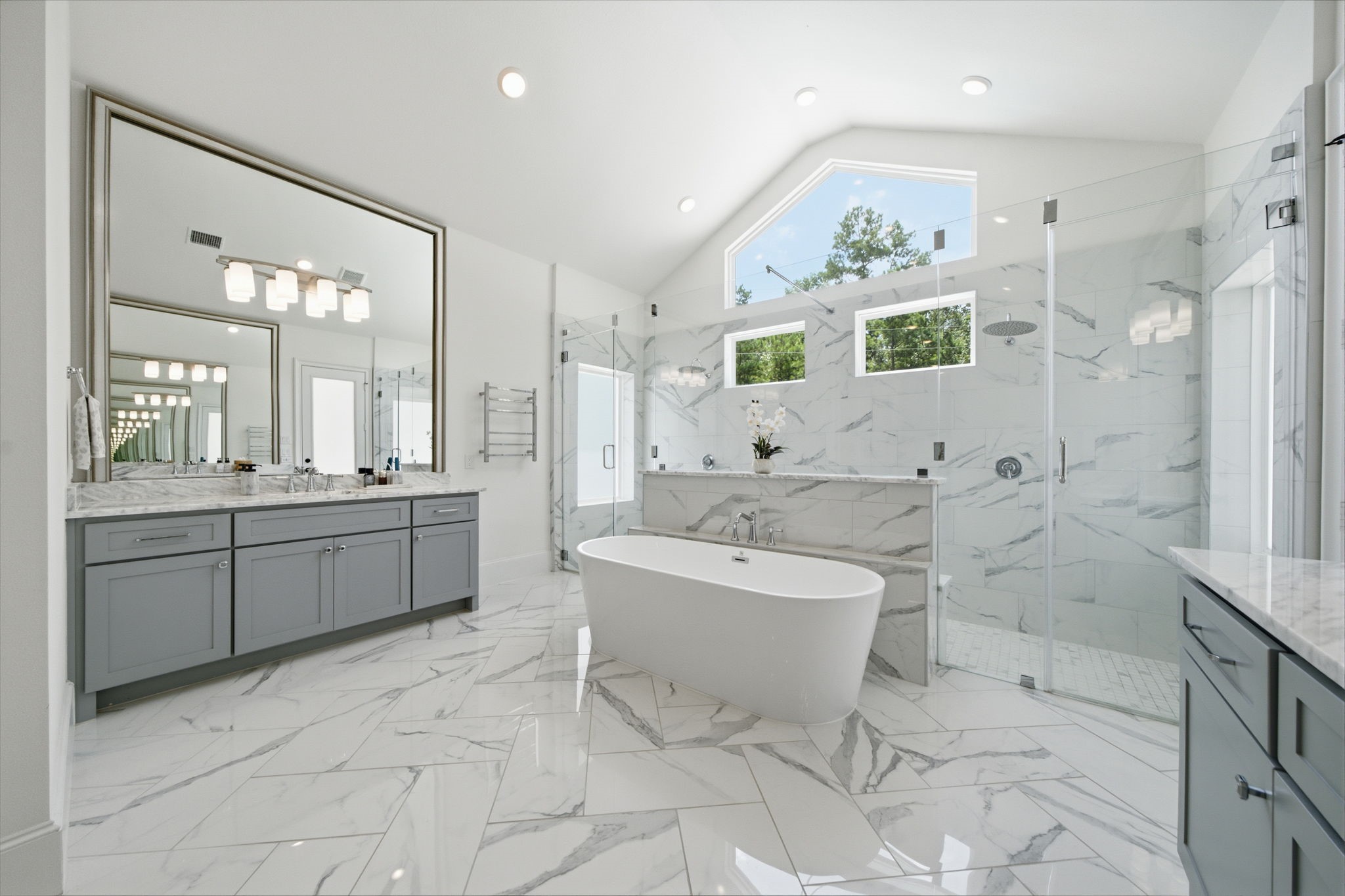 Luxurious bathroom featuring a freestanding tub, spacious glass-enclosed shower, and elegant double vanity with marble countertops.