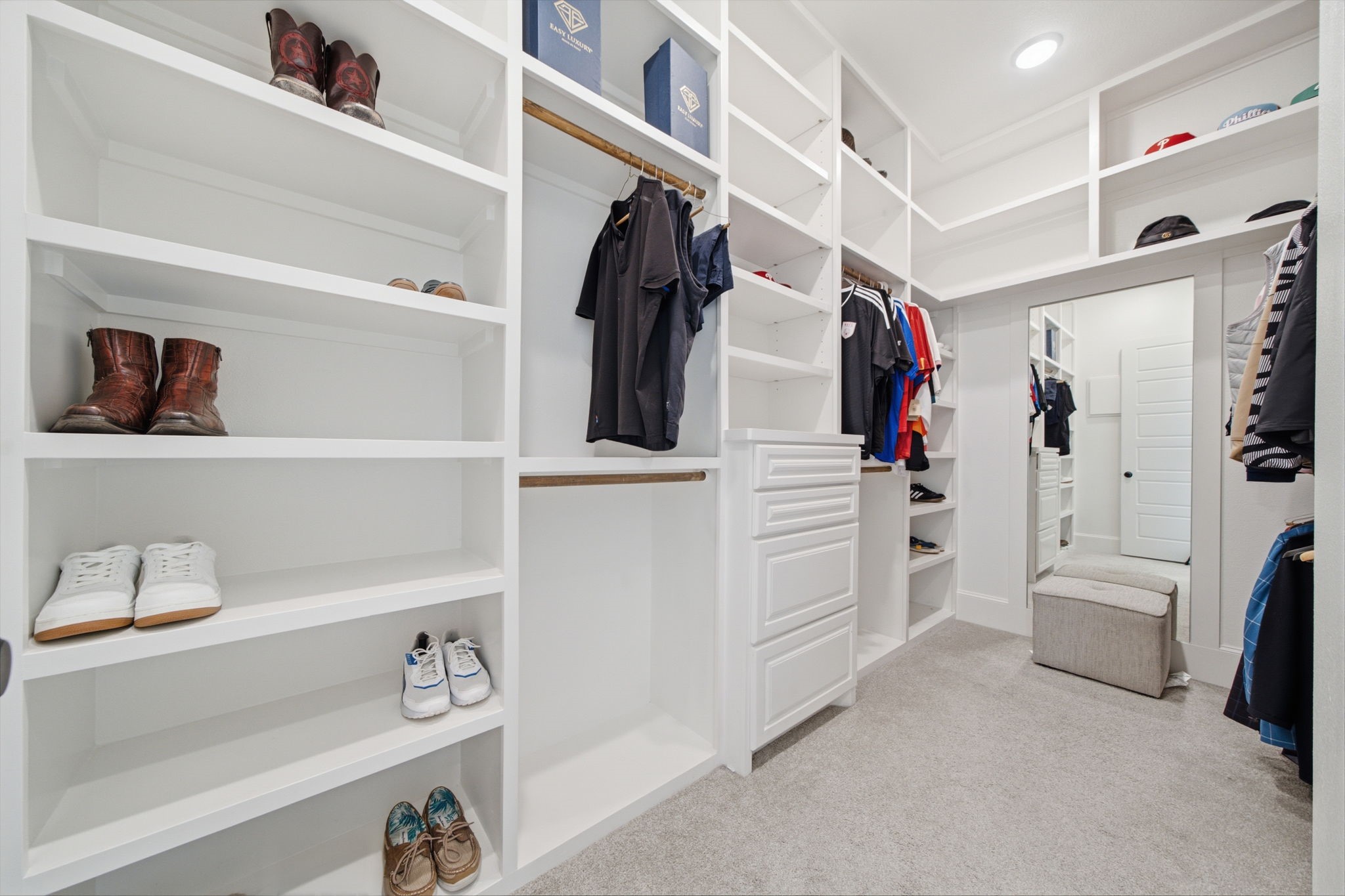 Spacious walk-in closet with custom shelving, ample hanging space, and a convenient built-in dresser, perfect for organized storage.