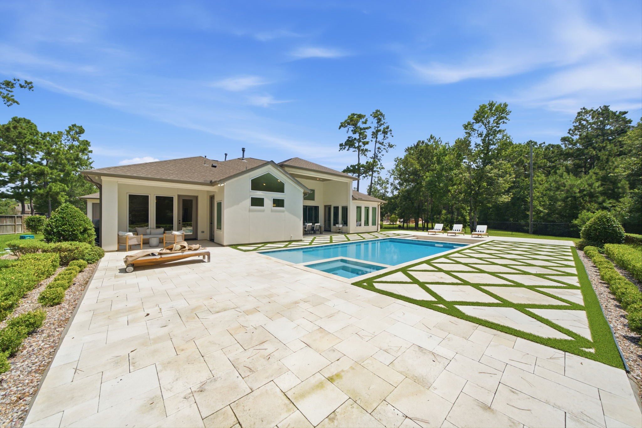 Elegant modern home with a spacious backyard featuring a pristine pool, stylish patio, and lush greenery, perfect for relaxation and entertaining.