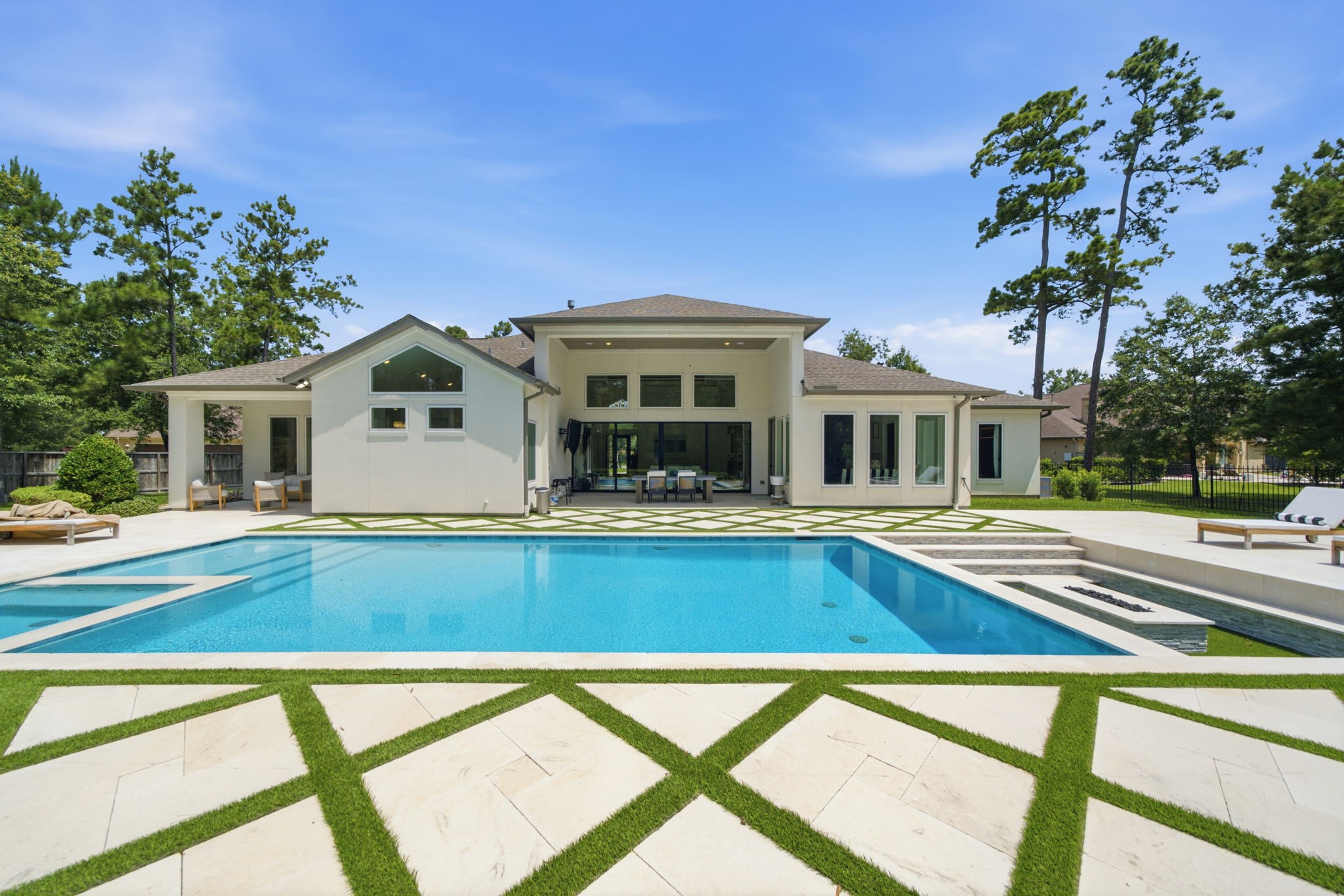 Luxurious modern home featuring an expansive backyard with a pristine swimming pool, surrounded by elegant landscaping and ample lounging areas for relaxation and entertainment.