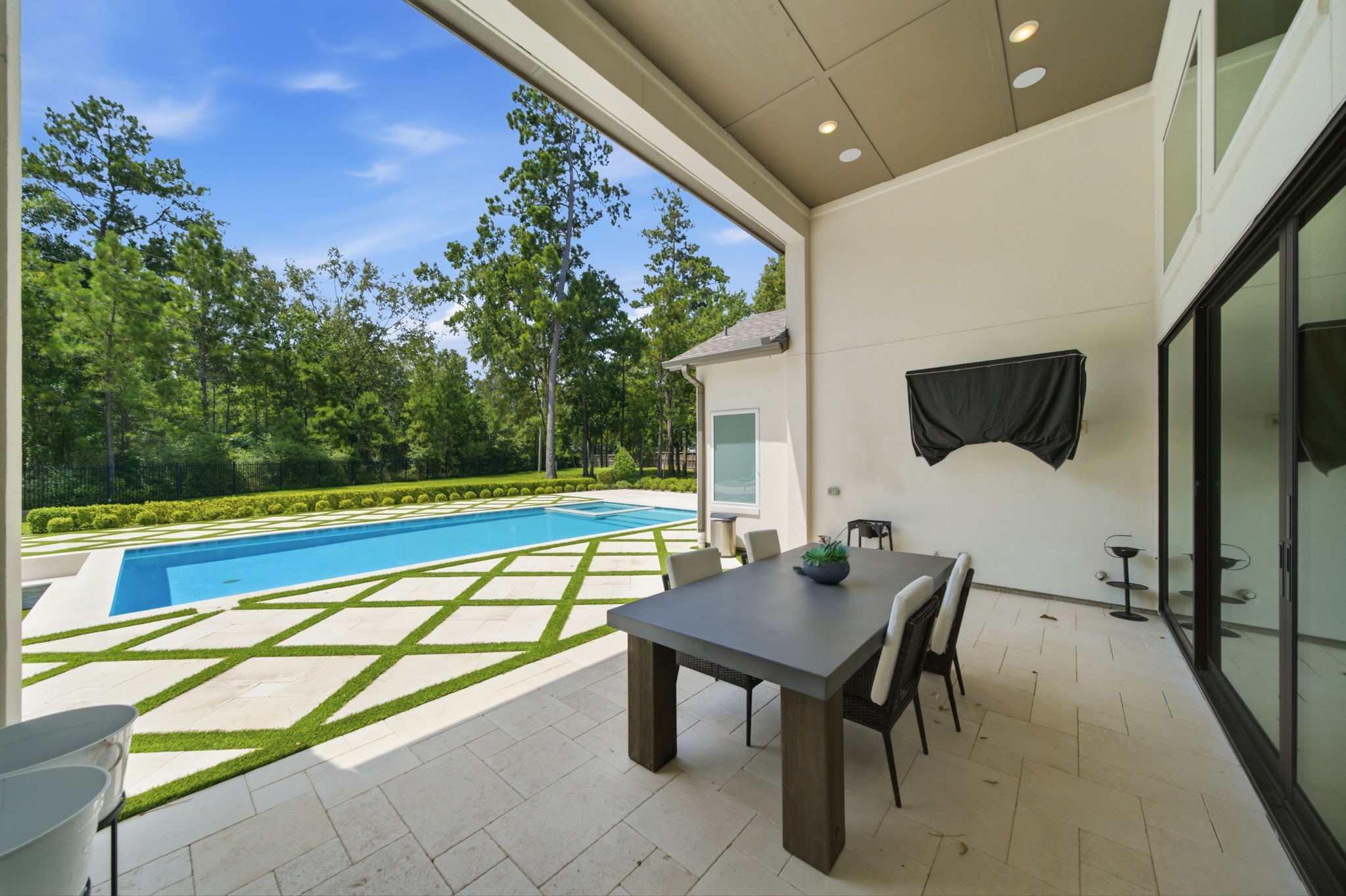 Discover seamless indoor-outdoor living with this elegant covered patio, overlooking a pristine pool and lush greenery.