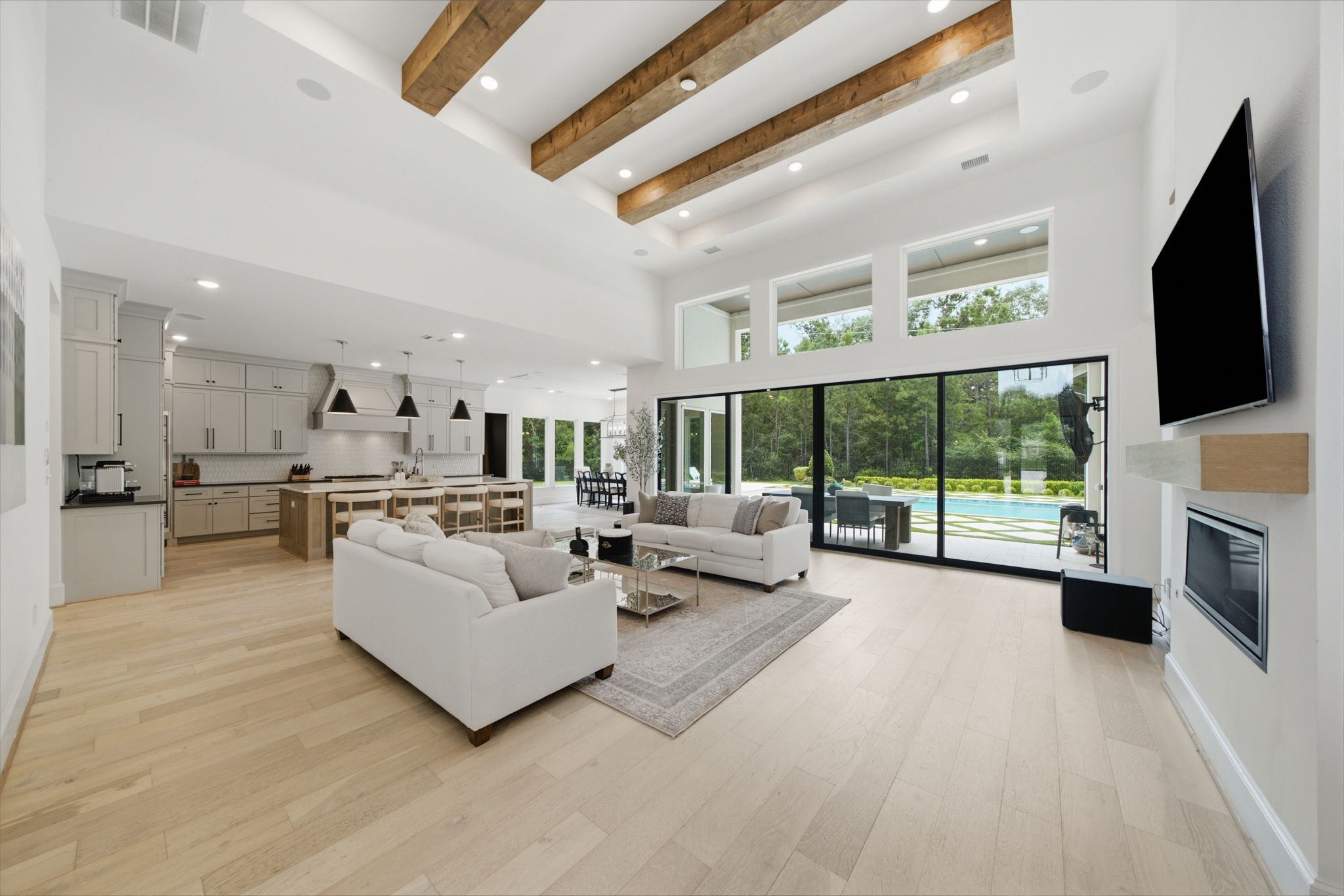 Stunning open-concept living area with high ceilings, exposed wooden beams, and expansive glass doors leading to a serene outdoor space. Stunning open-concept living area with high ceilings, exposed wooden beams, and expansive glass doors leading to a serene outdoor space.