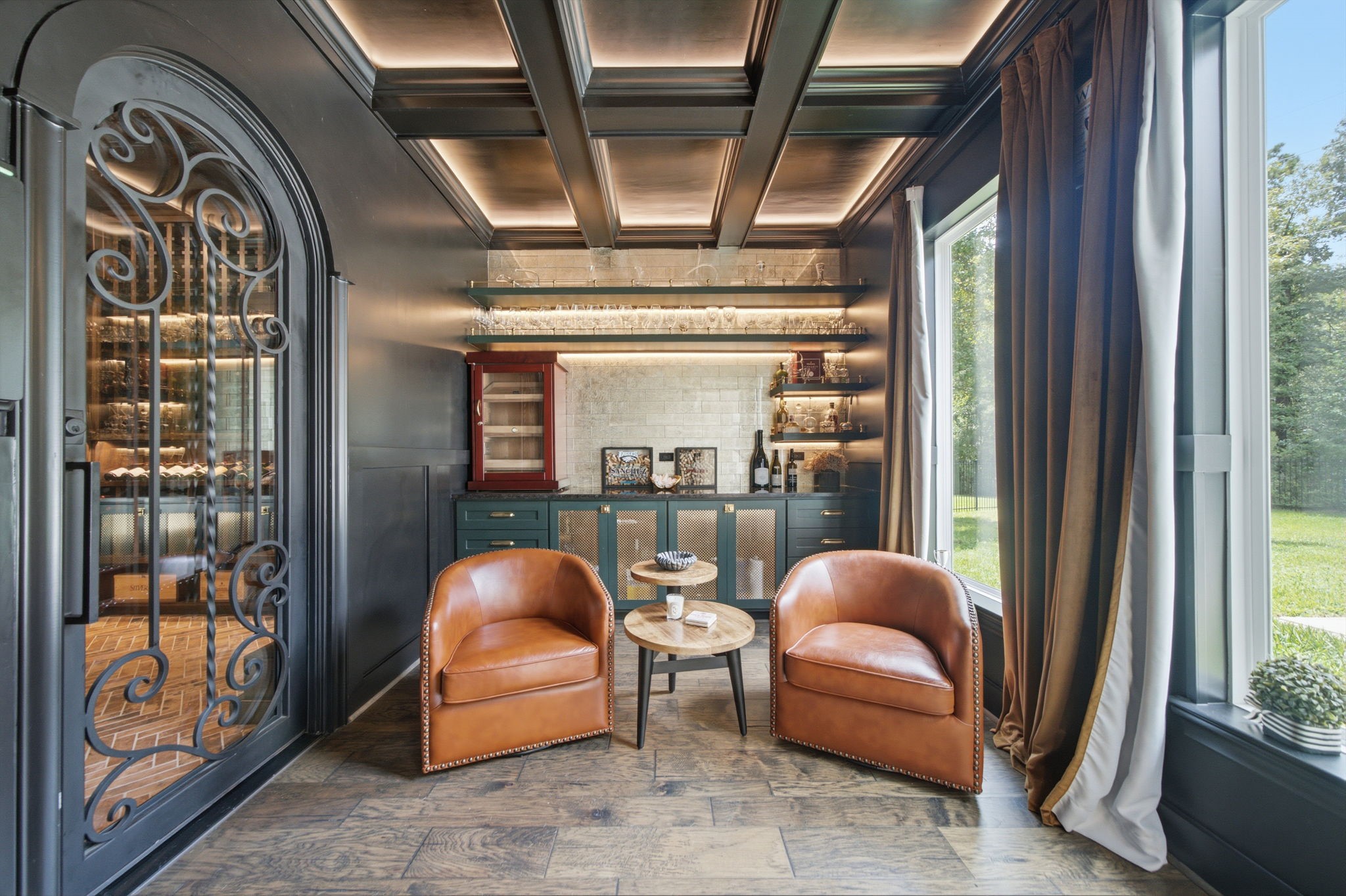 Elegant wine-tasting room featuring rich wood accents, leather seating, and a wall of glass overlooking serene greenery.