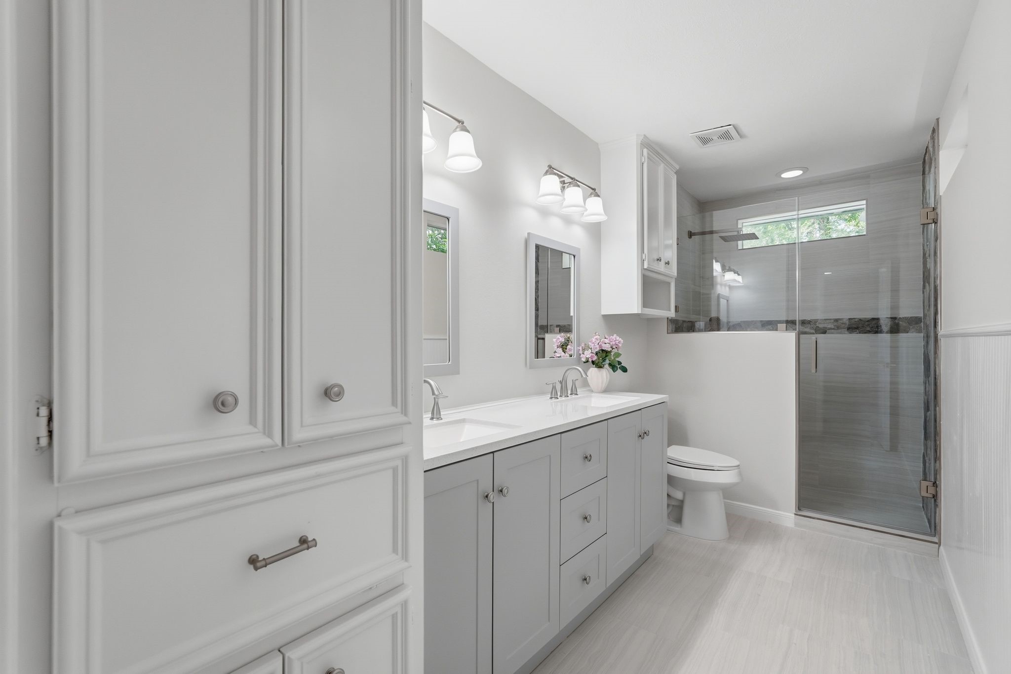 This second primary bathroom has a large double sink countertops, storage just inside the door and a spacious walk in shower.