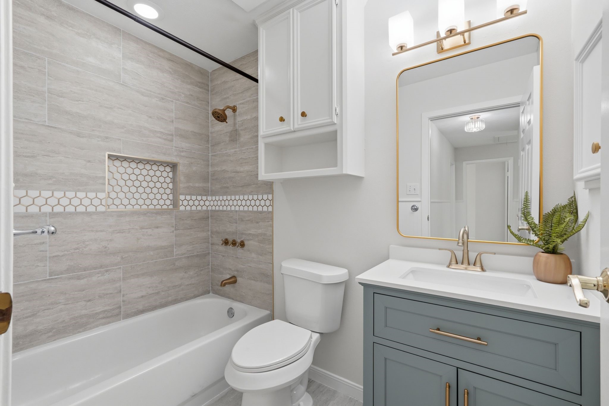 At the end of the hallway is a modern, updated bathroom with storage for toiletries and a bath/shower combo.