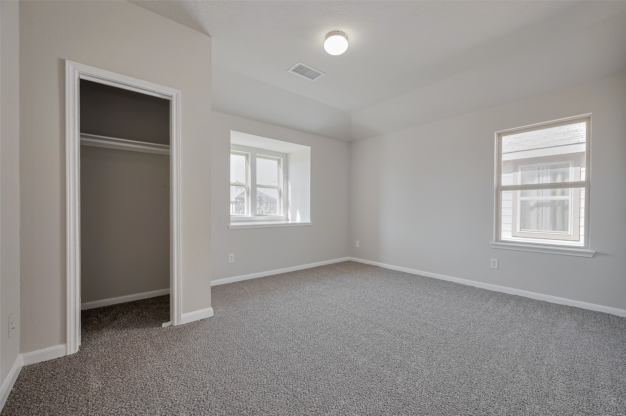 Bedroom with small closet, carpet, and two windows.