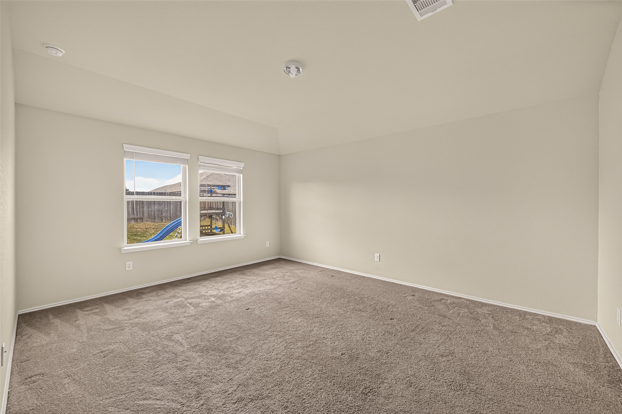 Master bedroom is huge and has big windows with carpet throughout.