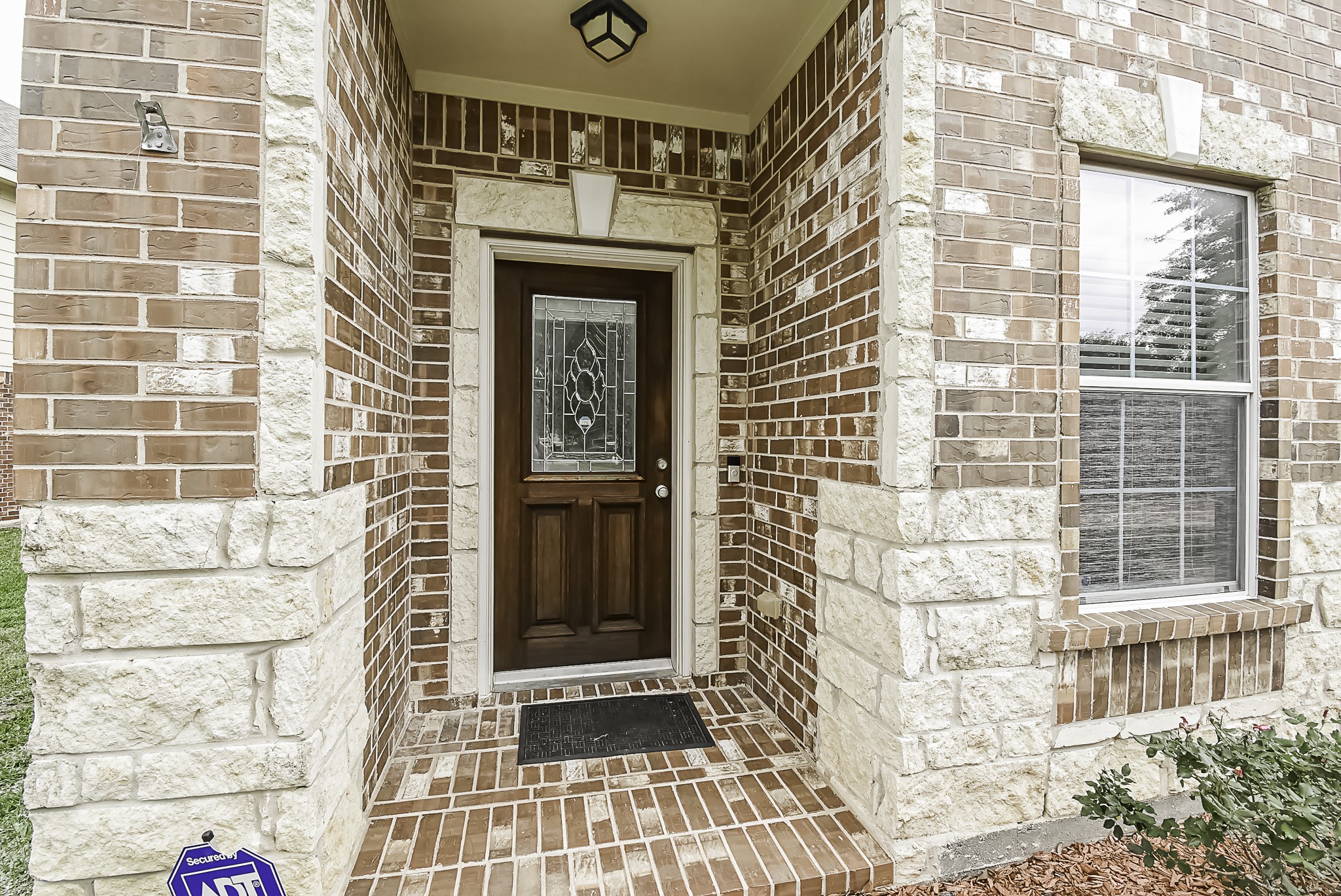 A brick-lined entryway leads you to the welcoming mahogany front door.