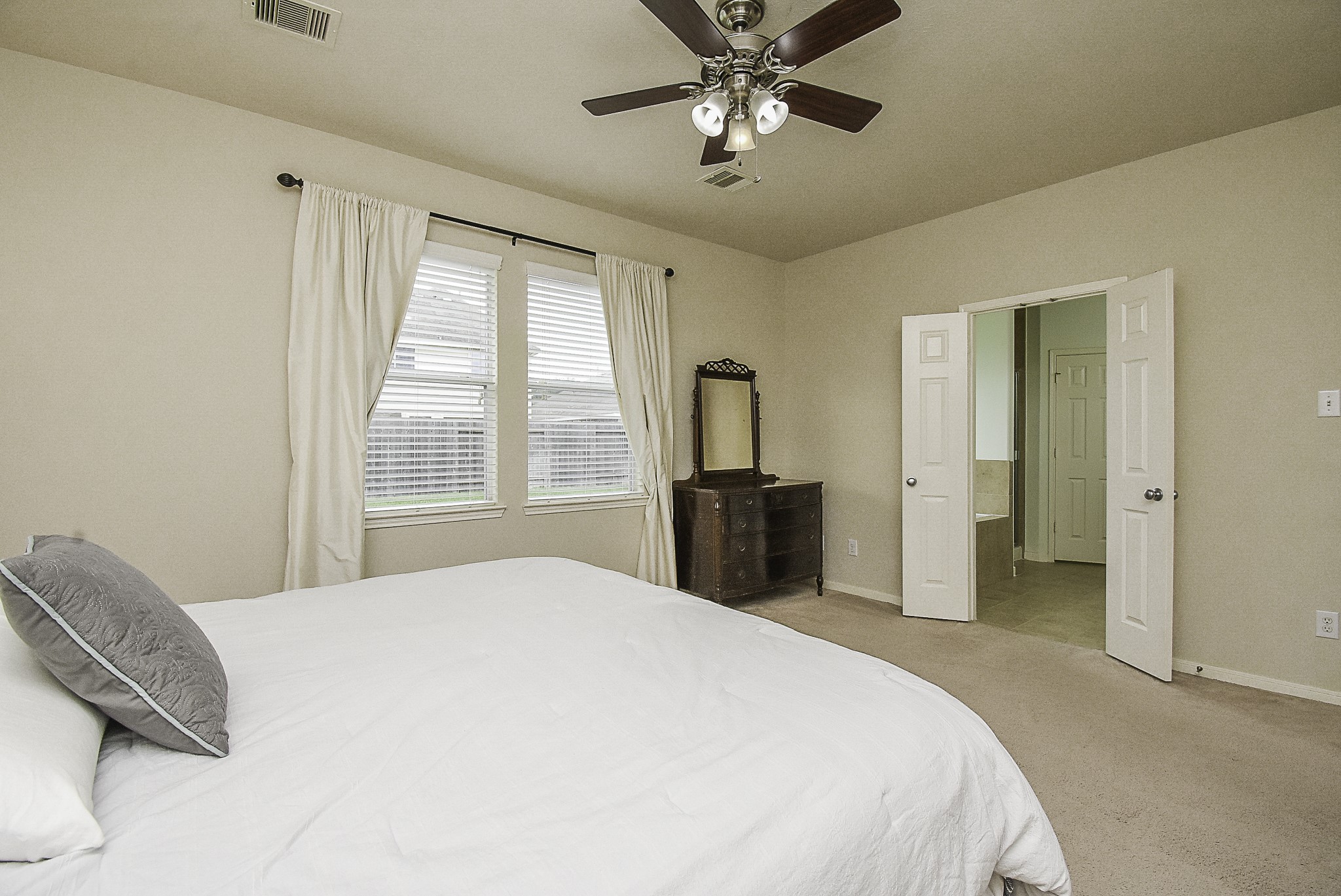 Another view of the spacious primary bedroom, featuring large windows, and direct access to the en-suite bathroom.