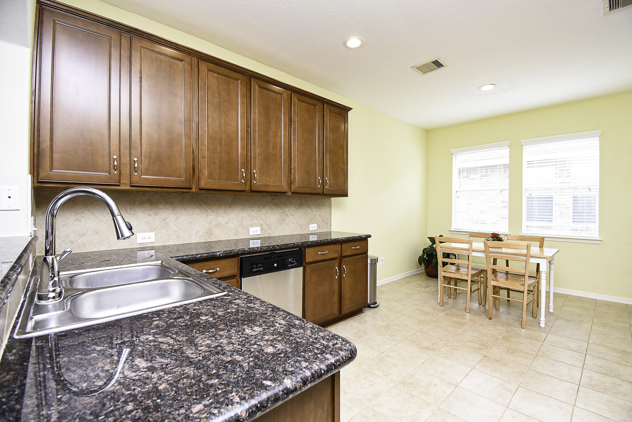 Wood cabinetry and granite countertops complement this spacious, open kitchen.