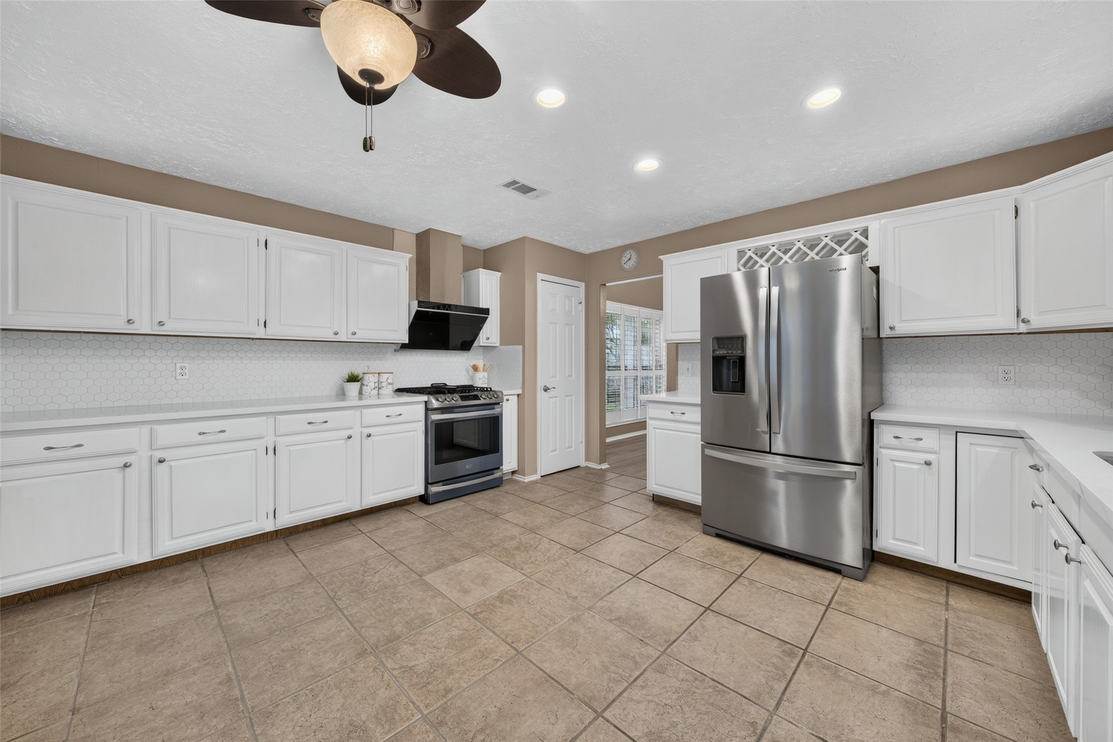 The bright, open kitchen boasts pristine white cabinetry, stainless steel appliances, and a custom built-in wine rack.