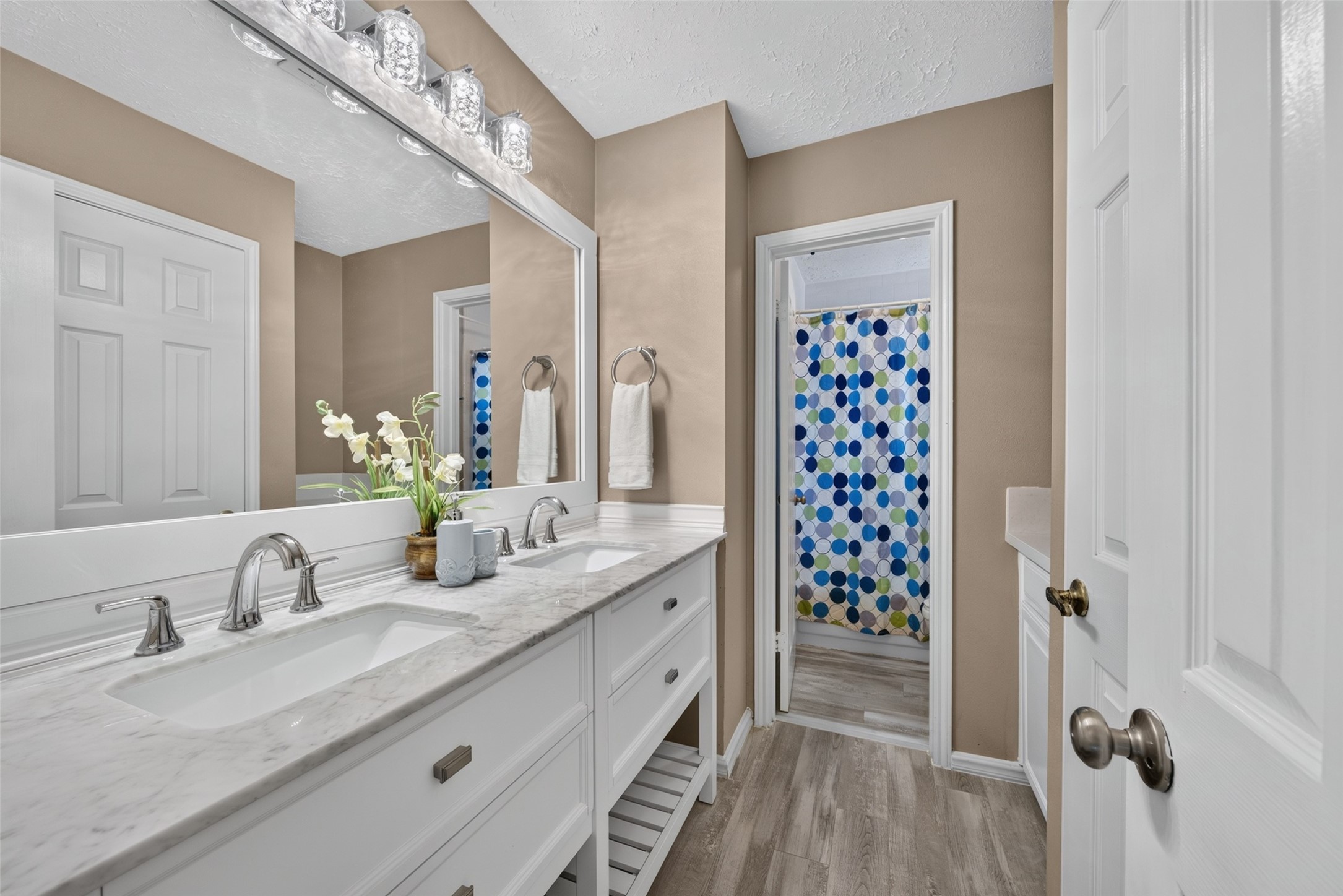 A full upstairs bathroom featuring a spacious double vanity with clean white cabinetry, generous counter space, and stylish updated finishes to easily accommodate family members and guests.