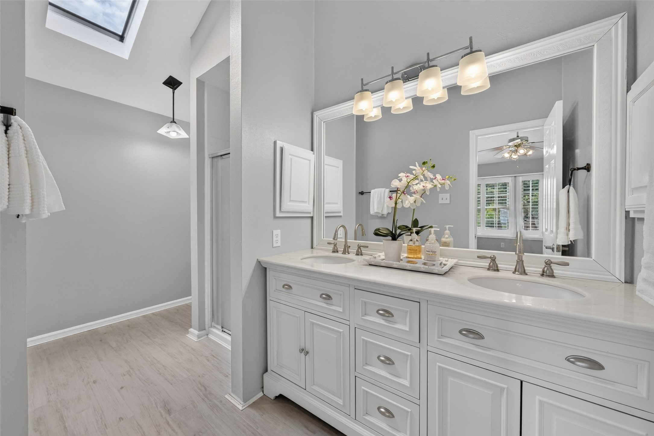 A bright and elegant primary ensuite bath featuring a double vanity with crisp white cabinetry, generous counter space, and updated fixtures designed for an effortless morning routine.