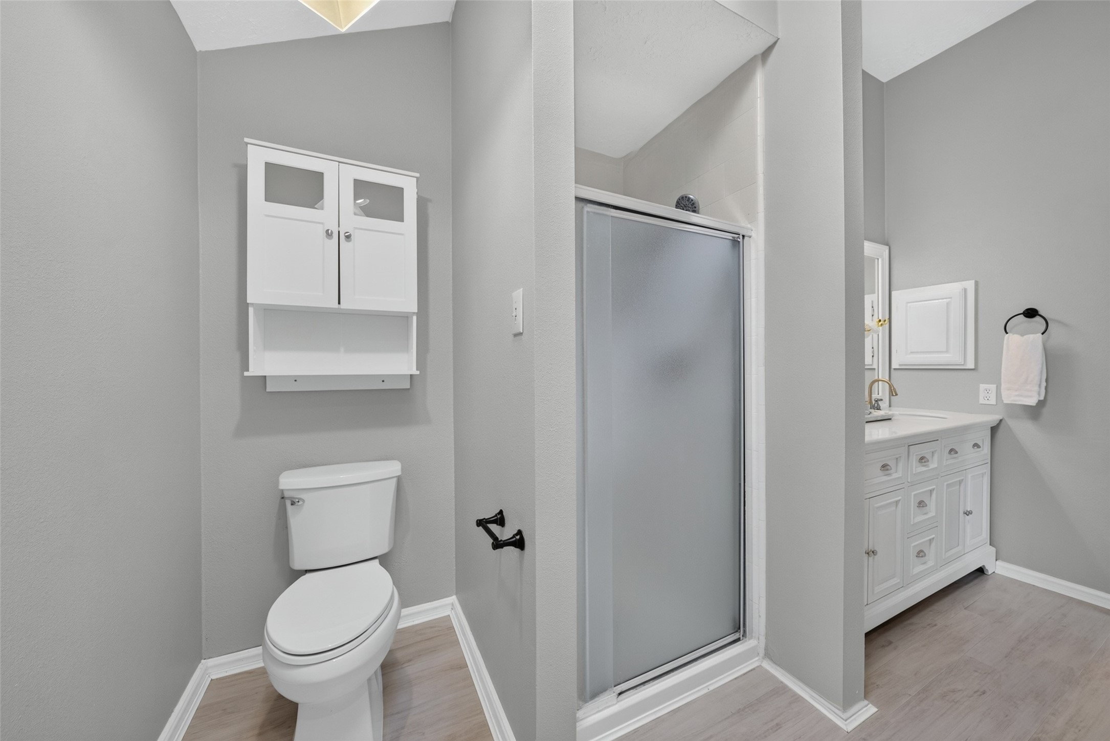A stylish primary en suite bath featuring a glass-enclosed walk-in shower and bright neutral tones.