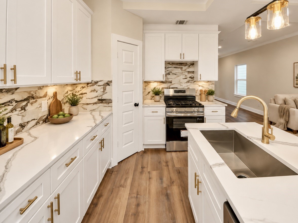 The kitchen combines white cabinetry, quartz countertops, contrasting hardware, and a decorative backsplash with stainless steel appliances, including an electric range, microwave, and dishwasher. | Virtually Staged