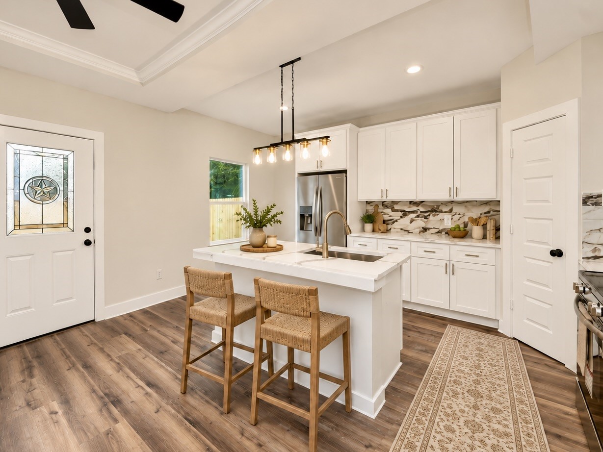 The kitchen features quartz countertops, a spacious center island, pendant lighting, white soft-close cabinetry, and a decorative backsplash. Stainless steel appliances and modern fixtures complete the design. | Virtually Staged