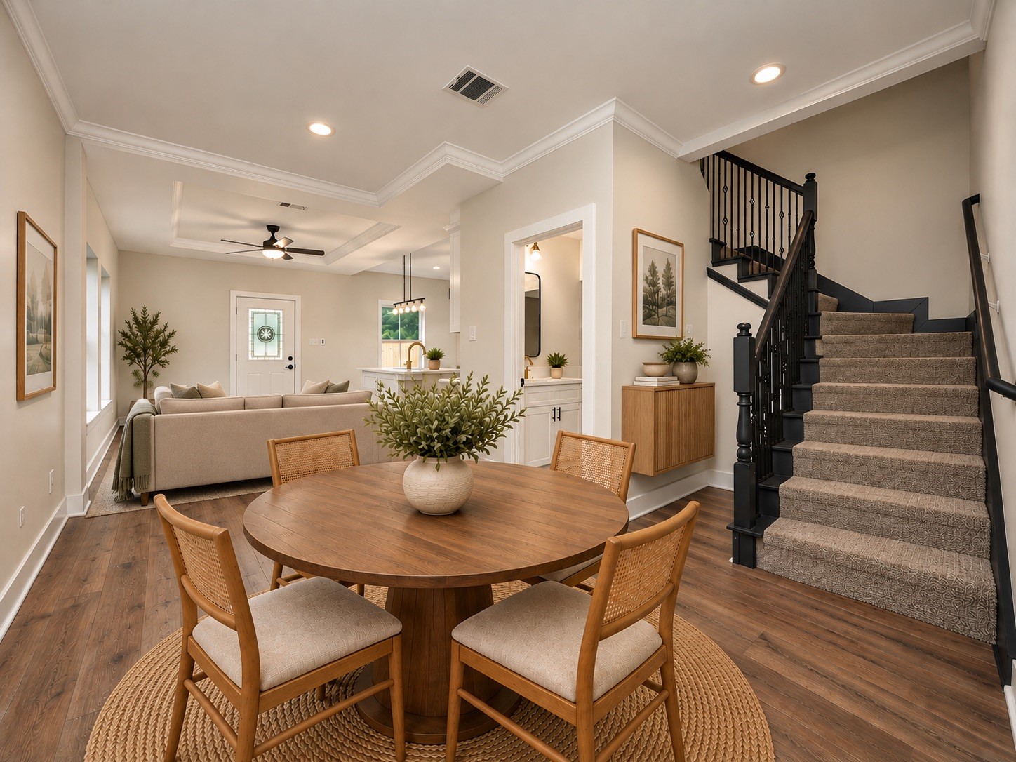 Step inside to an inviting open-concept layout featuring 9-foot ceilings, luxury vinyl plank flooring, crown molding, oversized baseboards, and recessed lighting. The dining area flows naturally into the family room and kitchen, while the staircase adds architectural character. | Virtually Staged