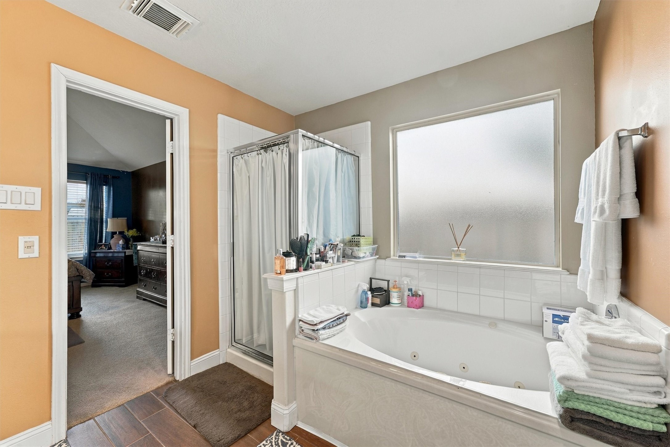 Spacious bathroom featuring a luxurious jetted tub, separate glass-enclosed shower, and a frosted window for privacy.