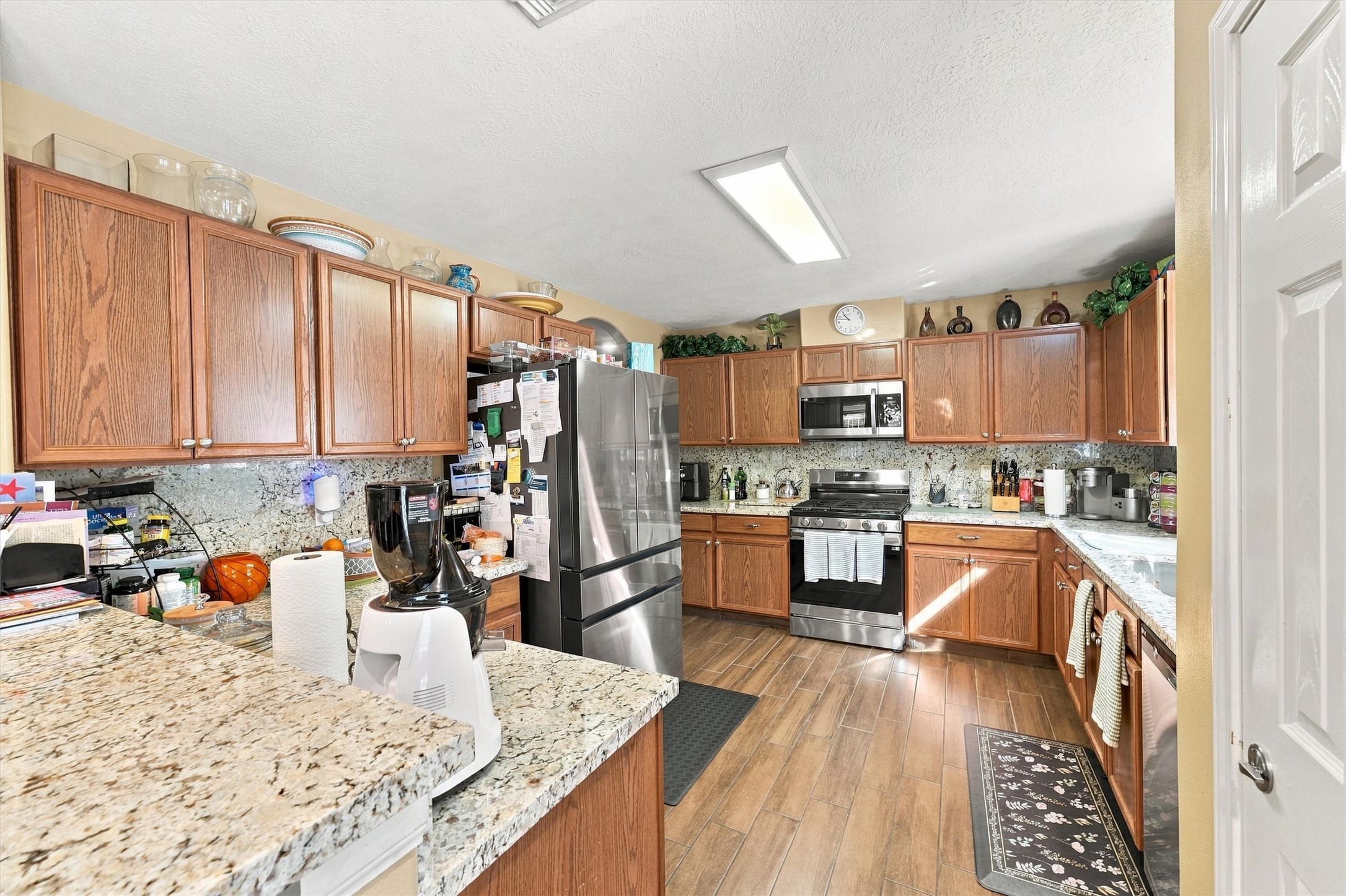 Spacious kitchen featuring granite countertops, stainless steel appliances, and ample wooden cabinetry for storage.