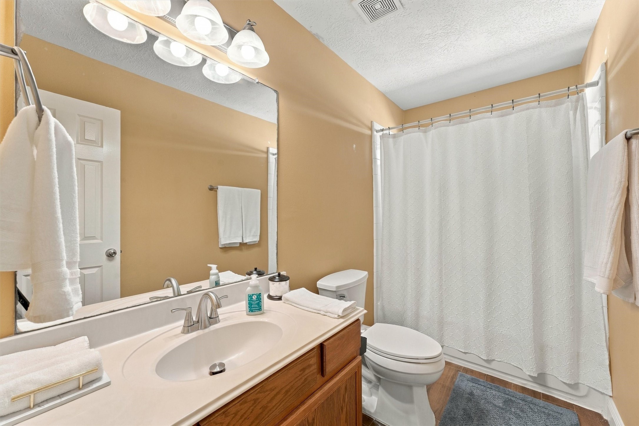 Bright and inviting bathroom featuring a spacious vanity with a large mirror, and modern lighting.