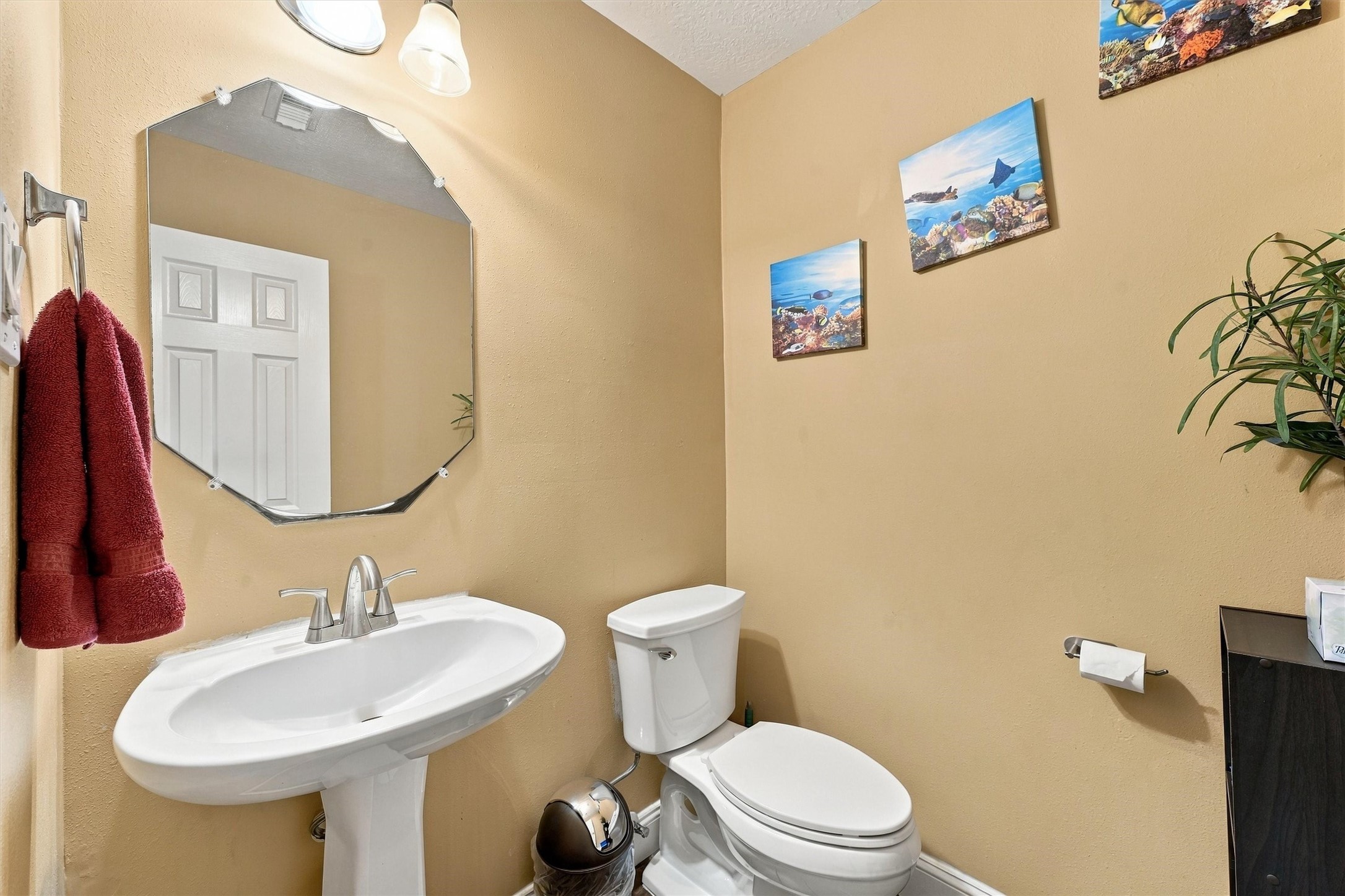 Charming bathroom features a pedestal sink, modern fixtures, and tasteful decor with warm-toned walls.