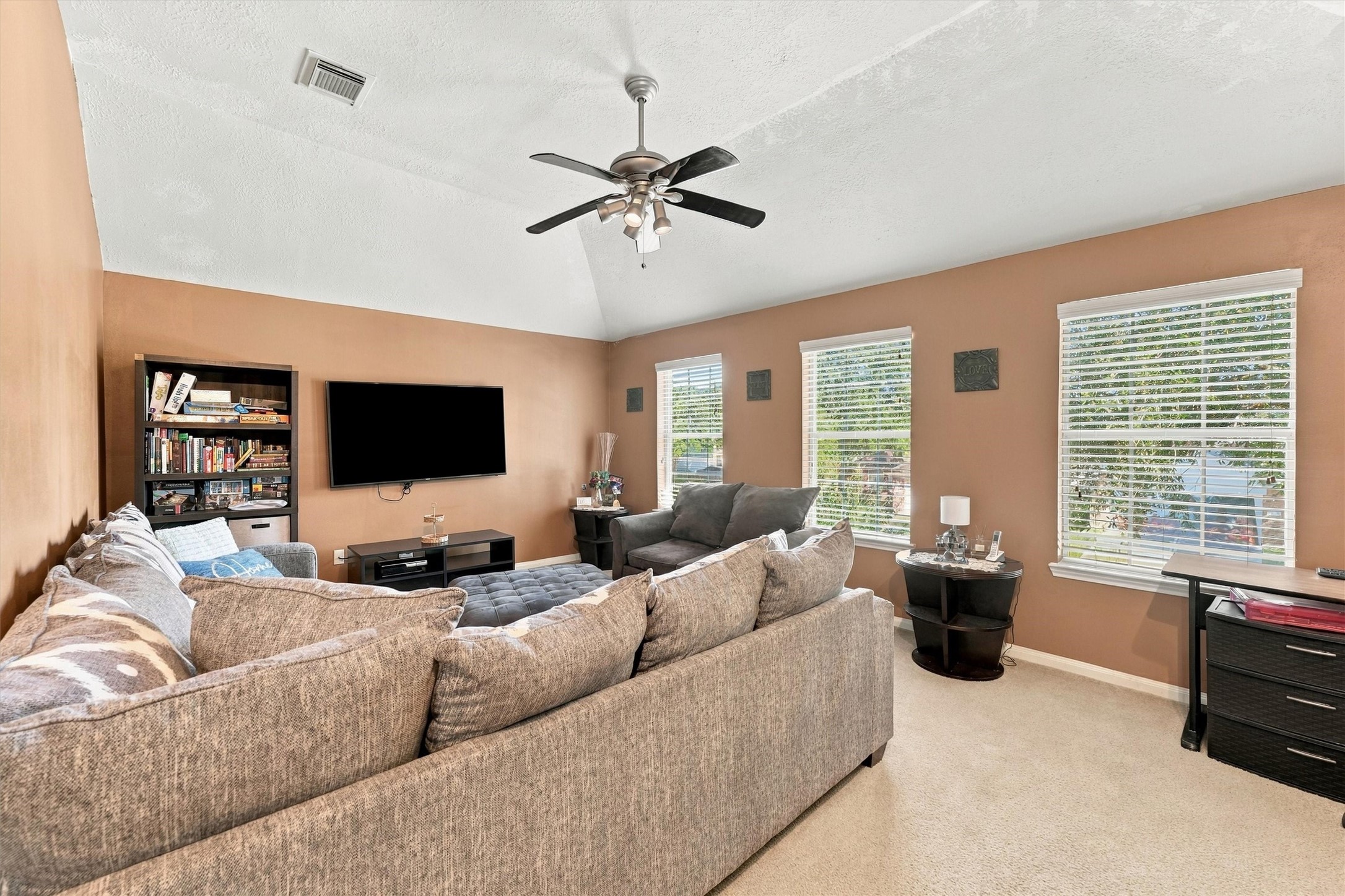 Inviting game room with vaulted ceilings, and abundant natural light from large windows. Cozy seating area perfect for relaxation and entertainment.