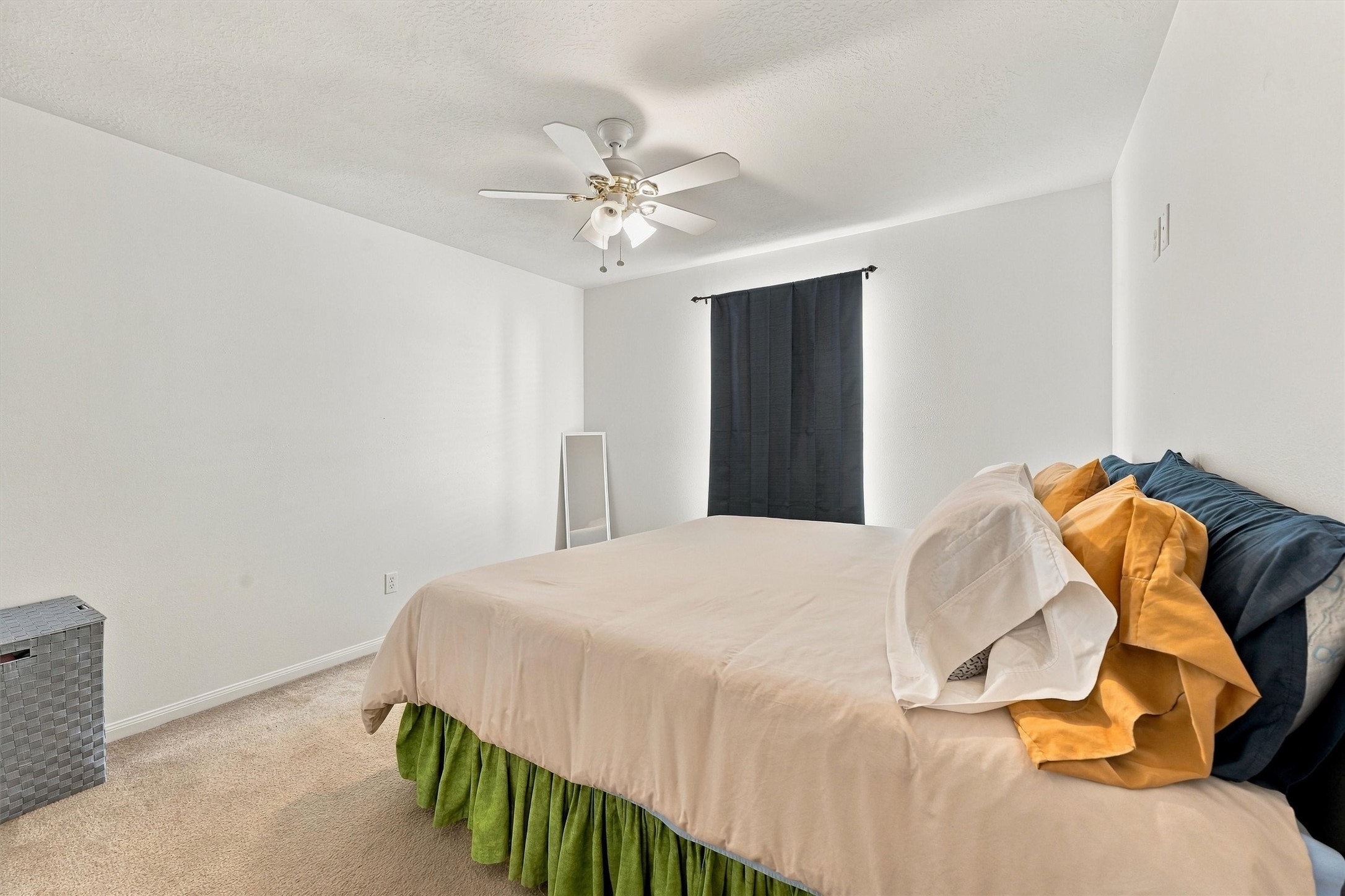 Bright and cozy bedroom featuring a ceiling fan, neutral tones, and a large window for natural light.