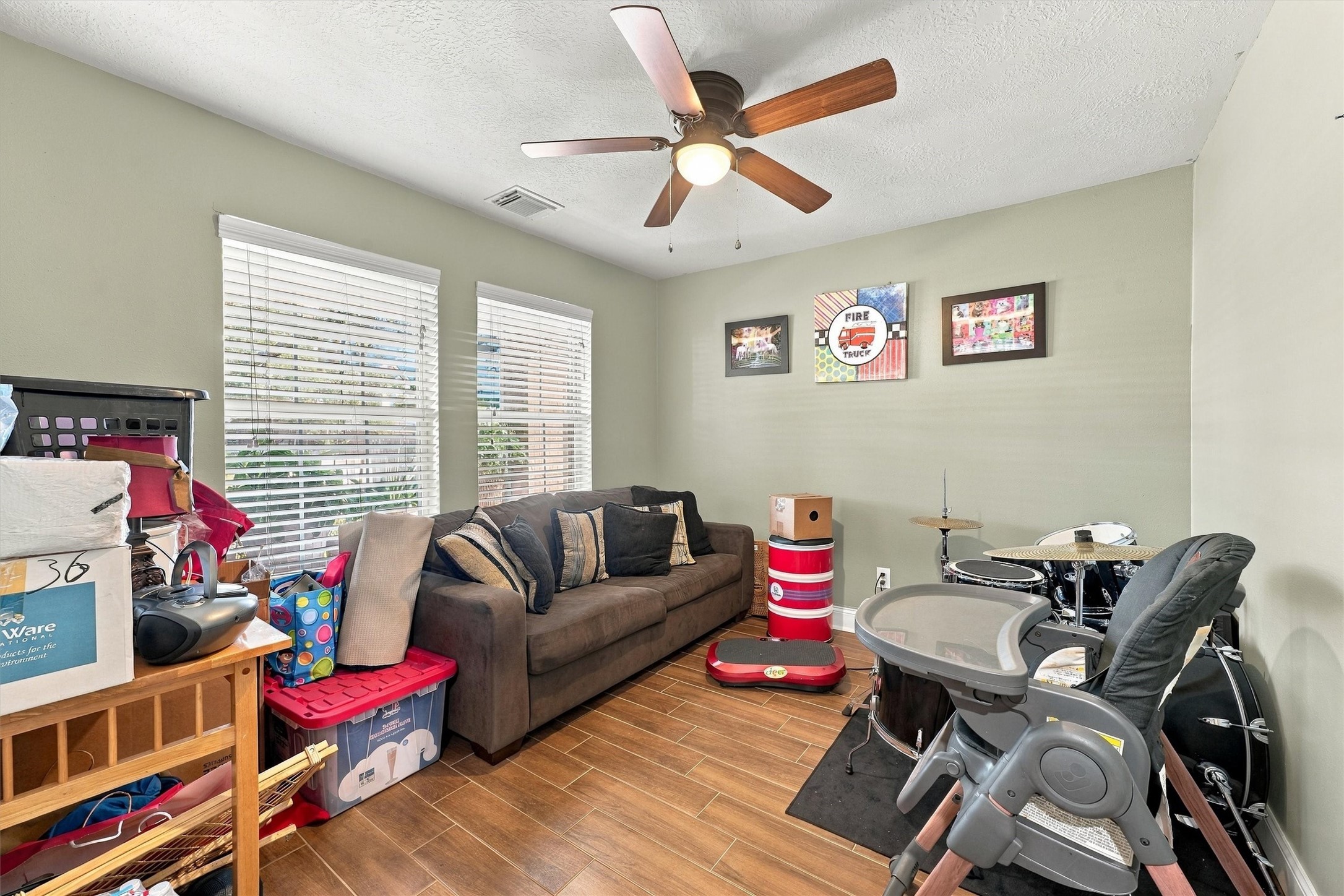 Cozy and versatile living space featuring large windows for natural light, a ceiling fan