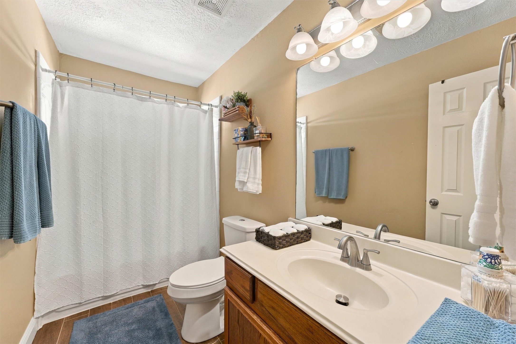 Bright and inviting bathroom featuring a large mirror, elegant lighting, and a spacious vanity with ample storage.