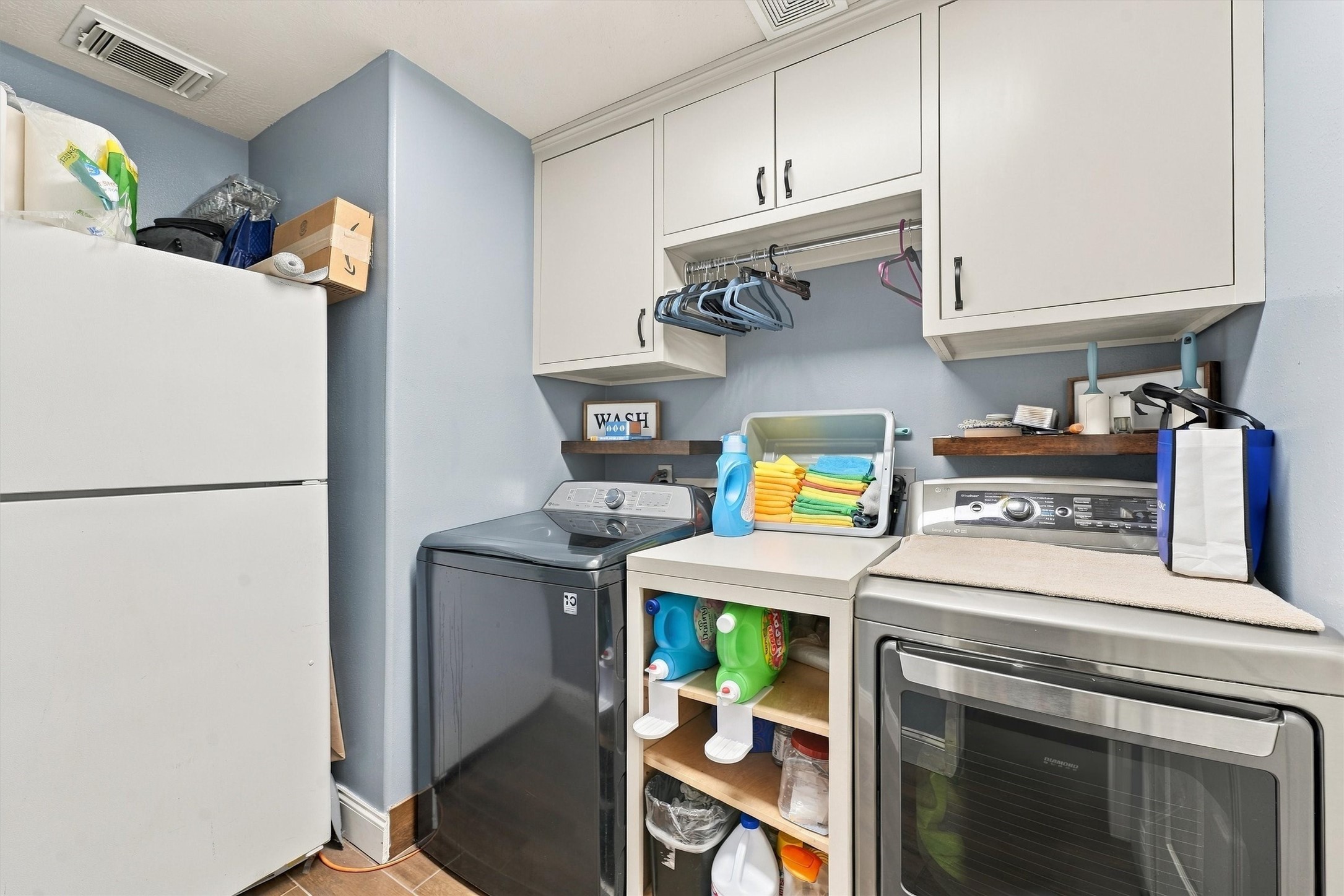 Efficient laundry room featuring modern appliances, ample cabinetry, and convenient shelving for organized storage.