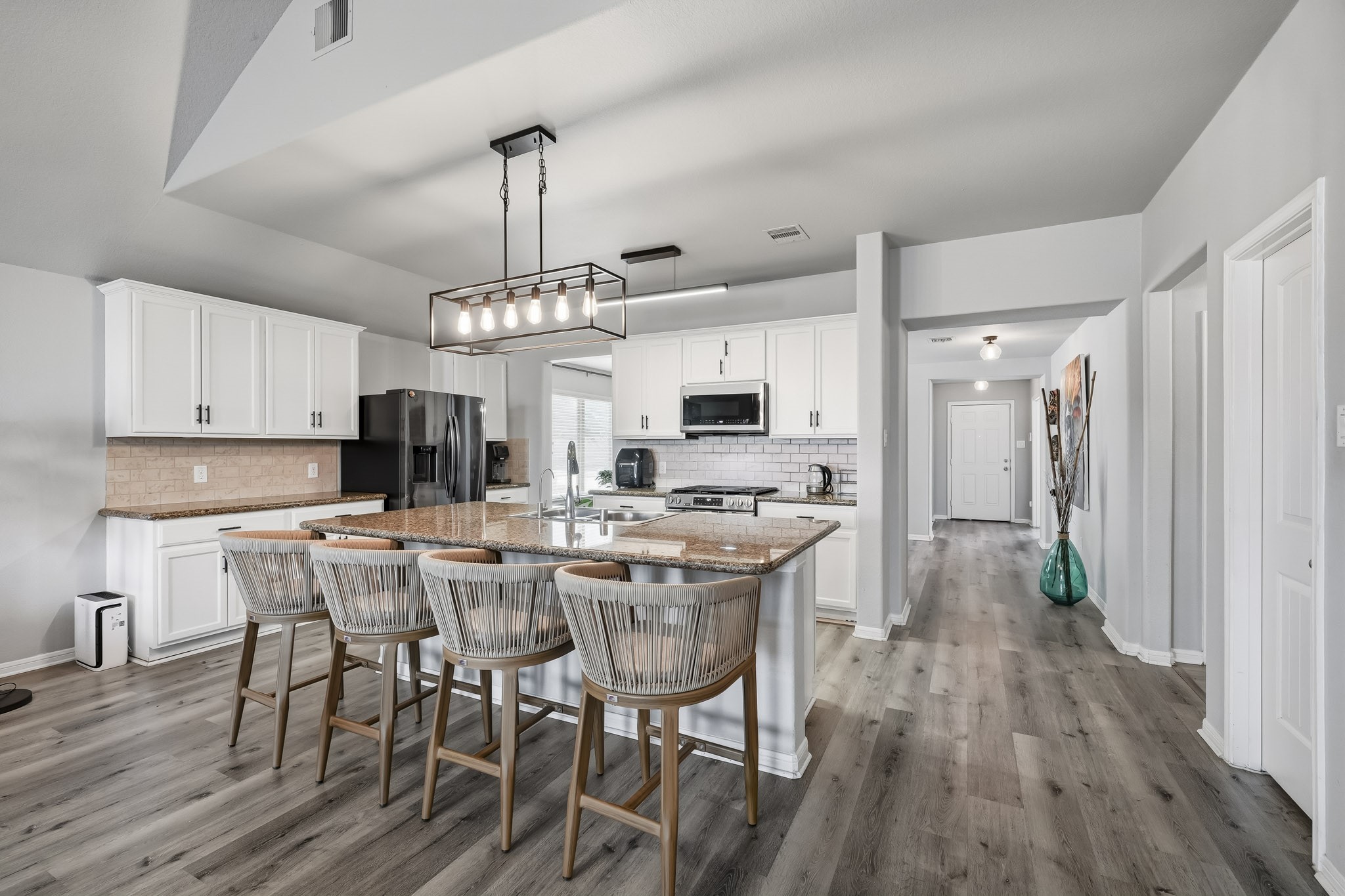 The spacious kitchen features white cabinetry, granite countertops, a large center island with bar seating, and an open design that connects beautifully with the main living areas. The spacious kitchen features white cabinetry, granite countertops, a large center island with bar seating, and an open design that connects beautifully with the main living areas.