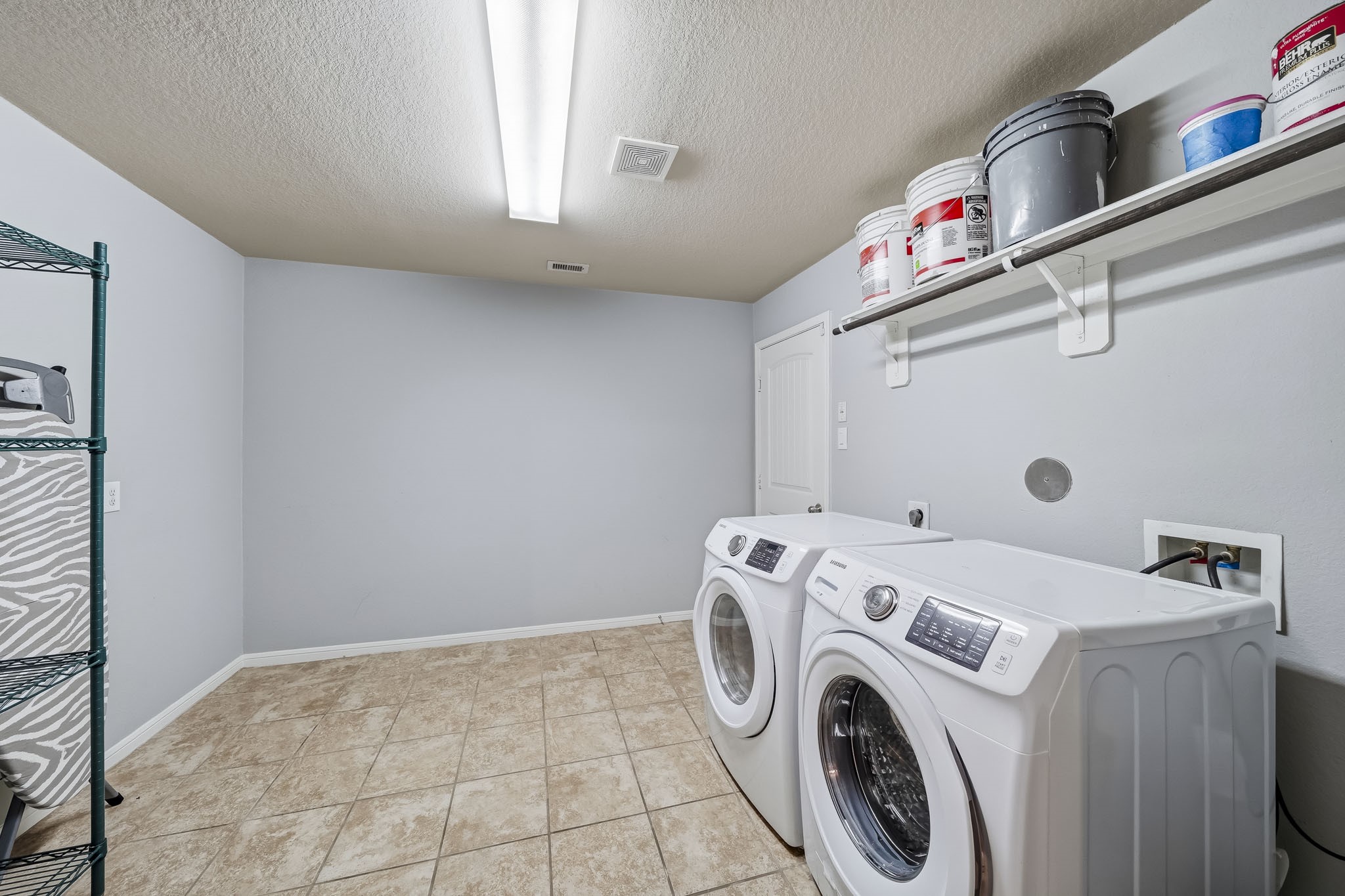 An oversized utility room offers generous floor space, built-in shelving, and a practical layout that makes everyday household tasks easy.