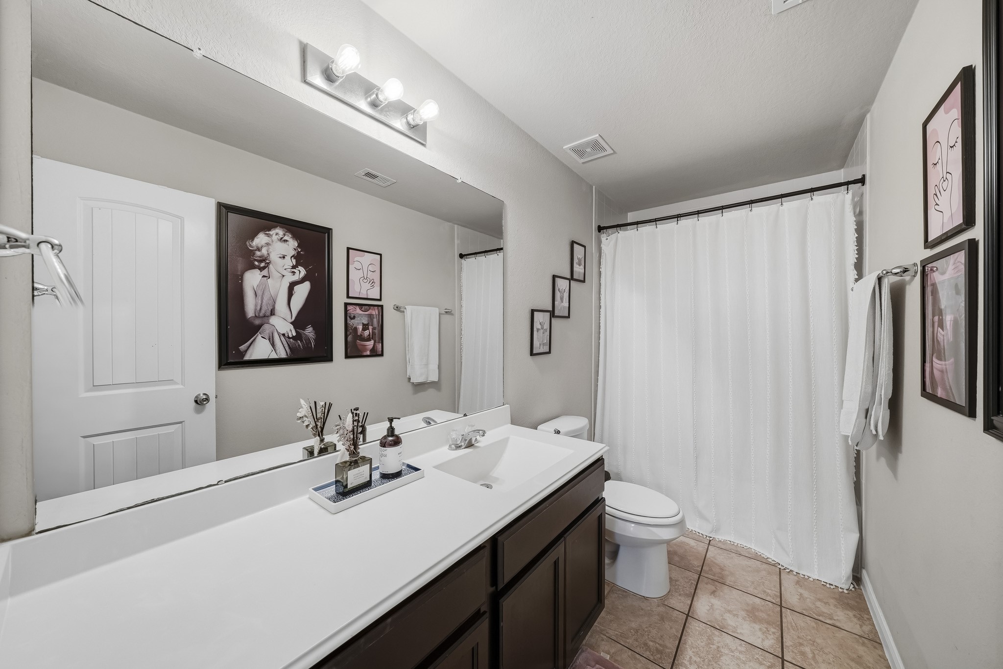A bright secondary bathroom features an extended vanity, generous counter space, and a shower and tub combination. A bright secondary bathroom features an extended vanity, generous counter space, and a shower and tub combination.