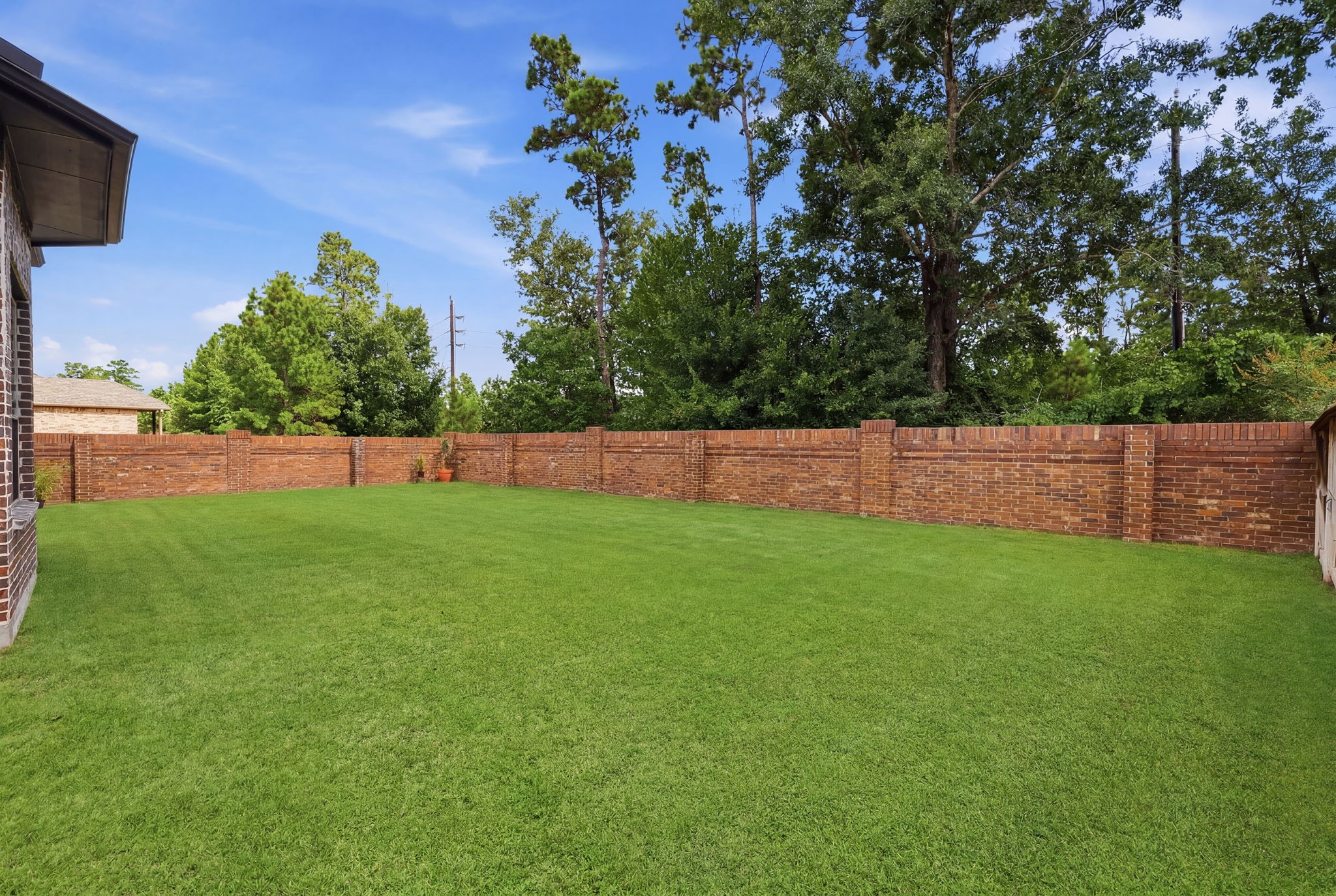 Low maintenance and visually appealing, a brick fence lines the corner of this spacious backyard.